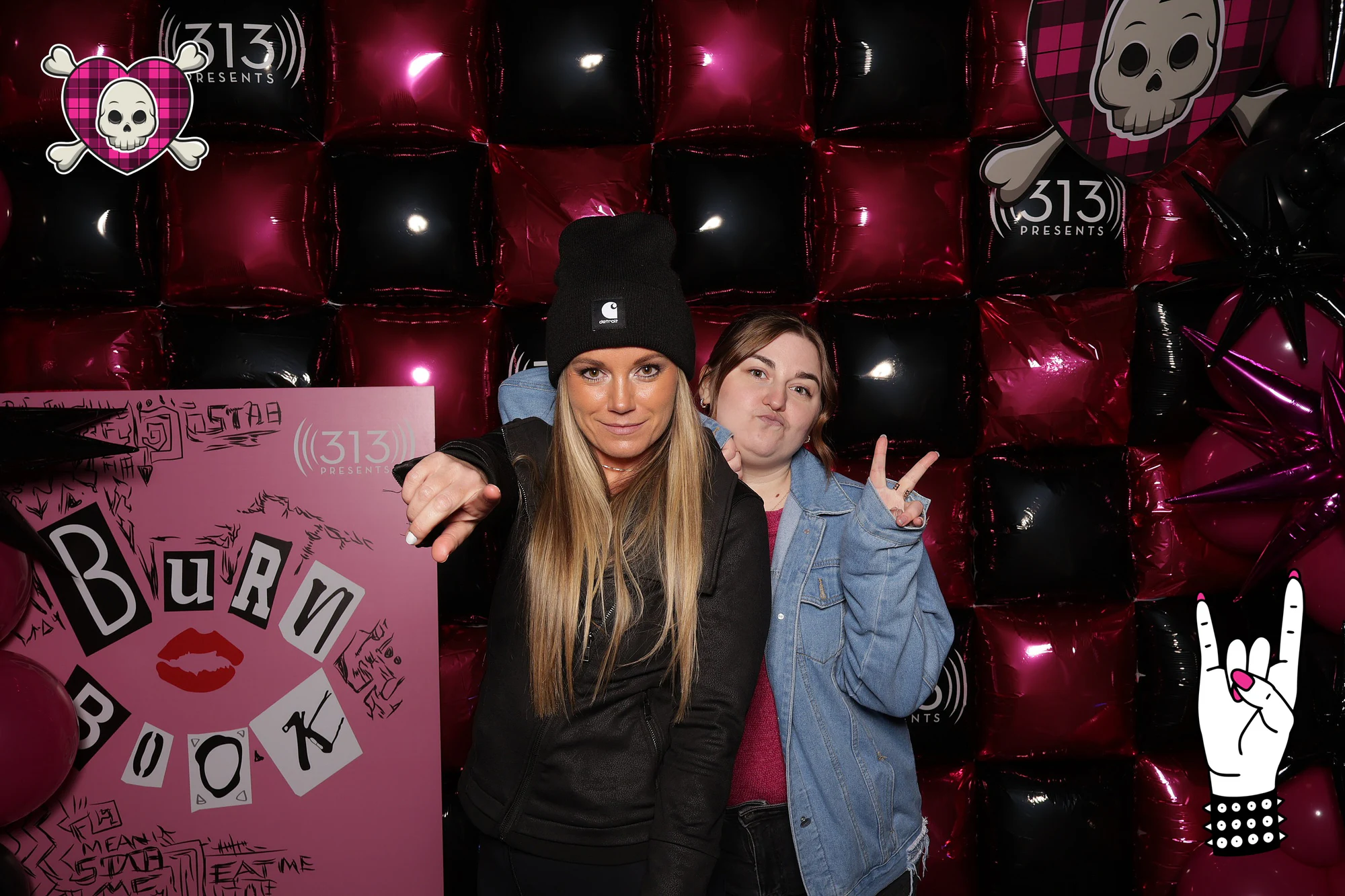 Two guests holding the Burn Book sign, one pointing at the lens, one throwing a peace sign at Avril Lavigne VIP Party at Pine Knob