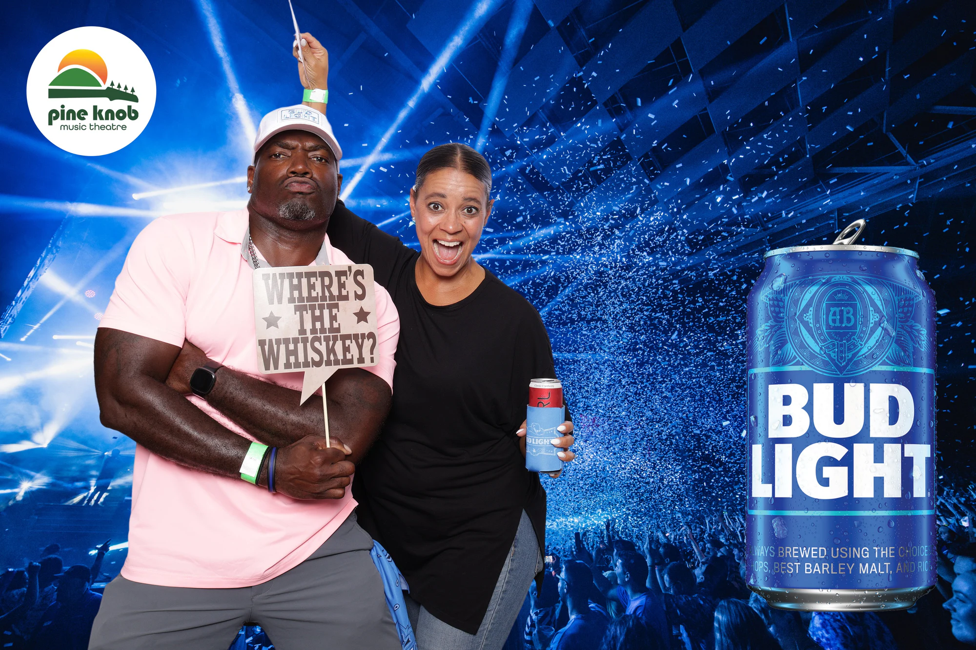 A guest holding a Where's the Whiskey sign, another beside him with a can at Bud Light Tailgate at Pine Knob, 2024