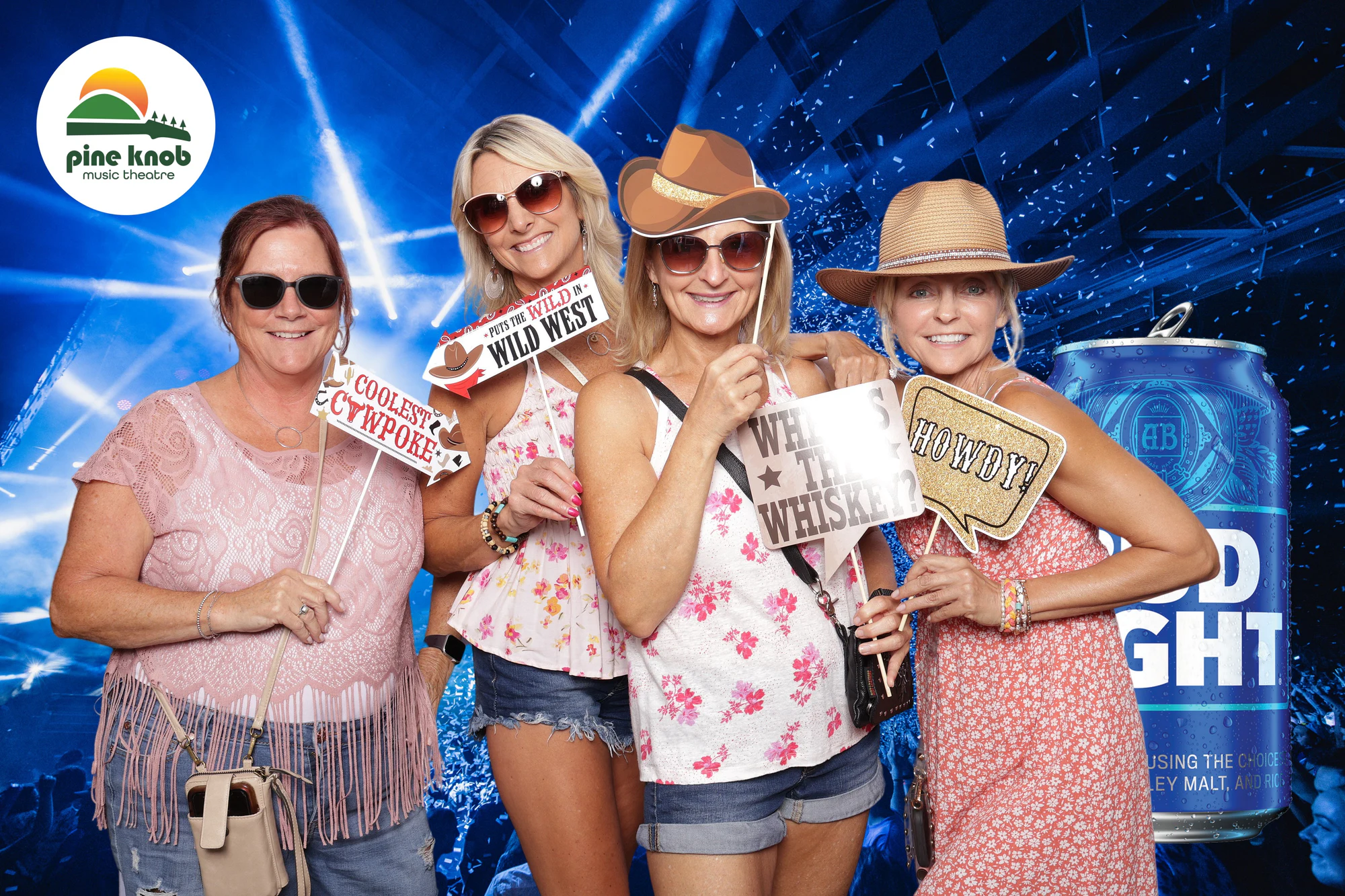 Four guests in straw and felt hats with Coolest Cowpoke, Where's the Whiskey and Howdy signs at Bud Light Tailgate at Pine Knob, 2024