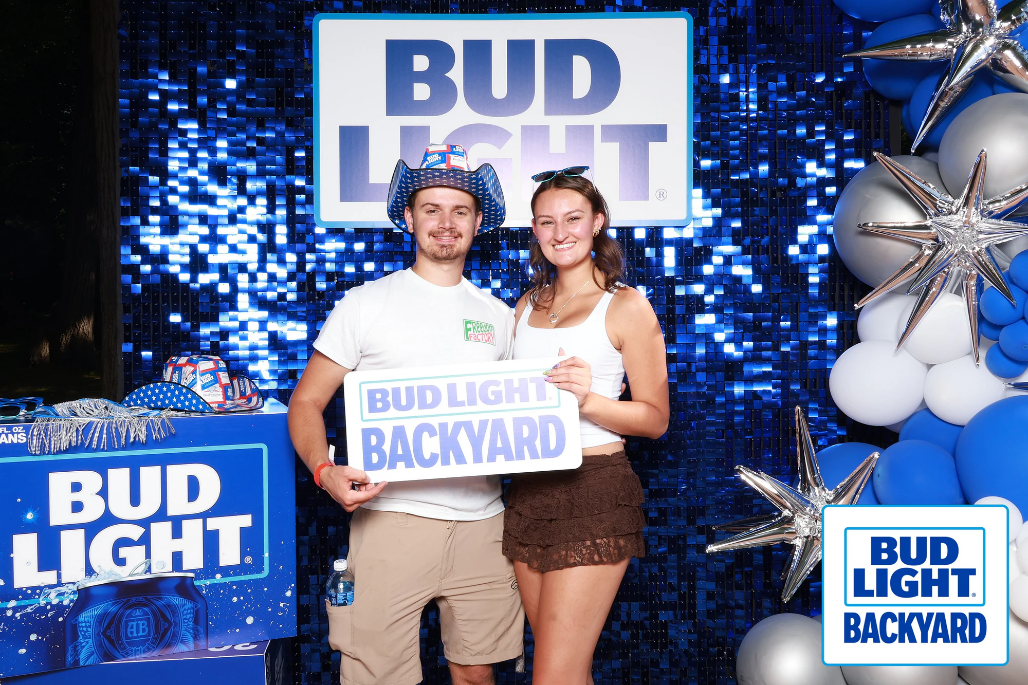 A couple holding the Bud Light Backyard sign, him in a Bud Light cowboy hat at Bud Light Tailgate for Luke Bryan, 2026