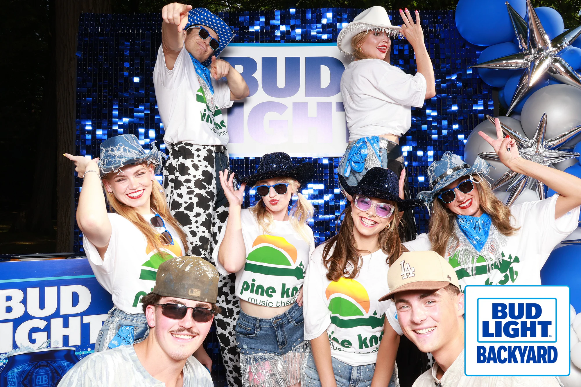 Eight guests in matching Pine Knob shirts and sequin cowboy hats, stacked three rows deep at Bud Light Tailgate for Luke Bryan, 2026