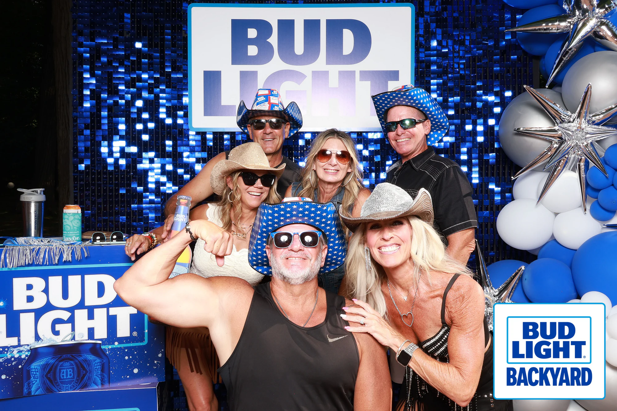 Six guests in cowboy hats and sunglasses stacked two rows deep at the sequin wall at Bud Light Tailgate for Luke Bryan, 2026