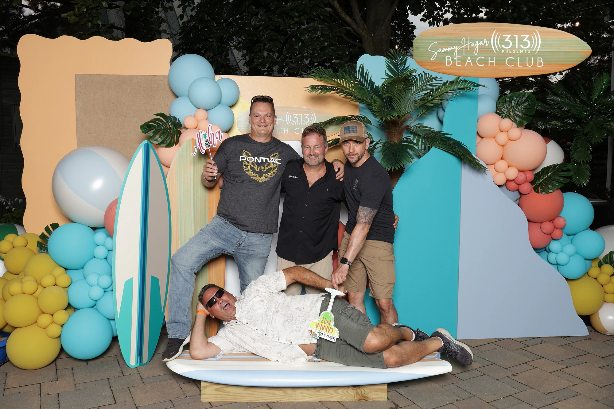Five friends, one stretched out on the surfboard prop at 313 Presents Concert Activations