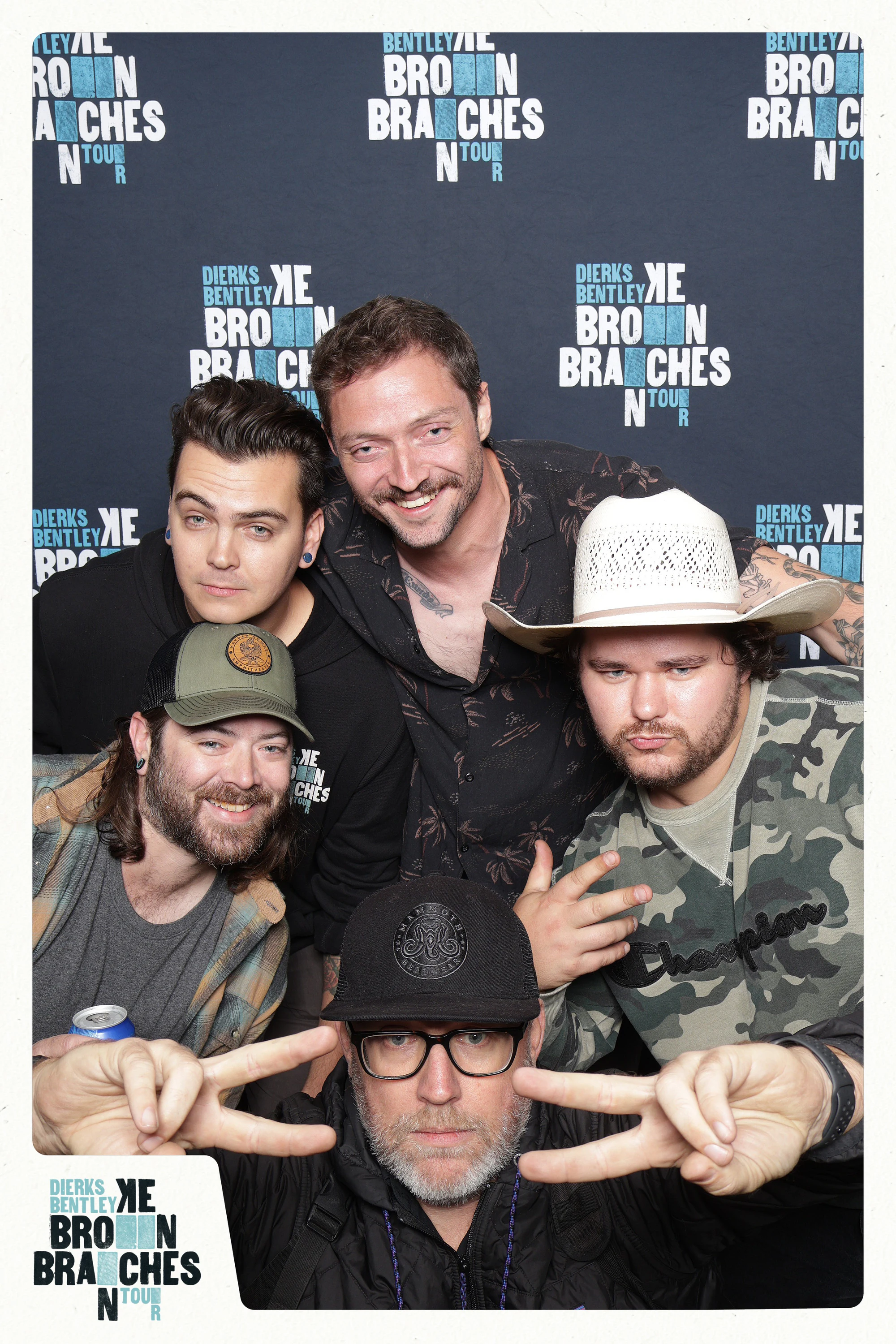 Five guests stacked at the tour wall, the one in front throwing double peace signs at Dierks Bentley End of Tour Party
