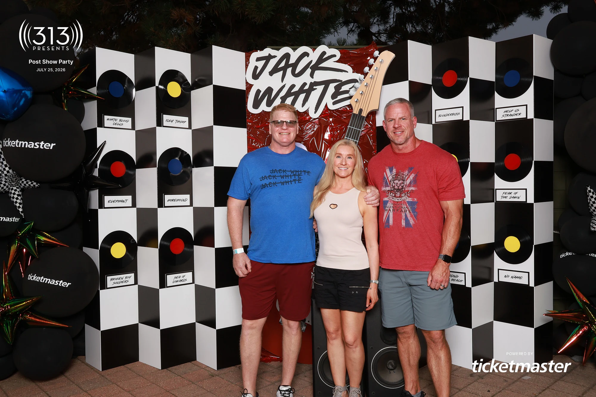 Three guests in front of the guitar backdrop at Jack White Post-Show Party at Pine Knob