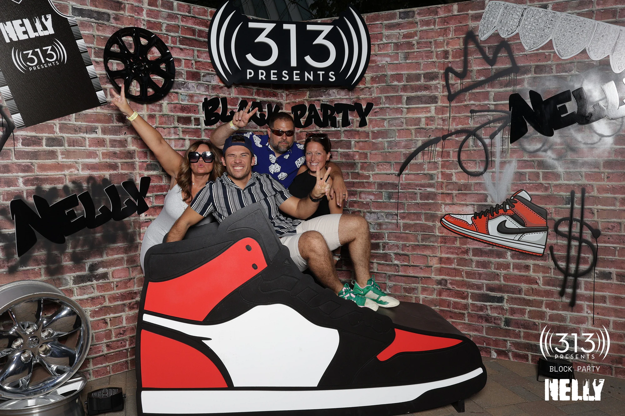 Four guests on the giant sneaker, one with an arm thrown up at Nelly Block Party with 313 Presents