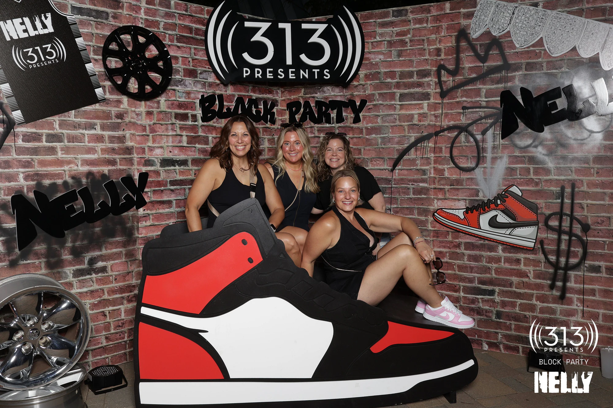 Four guests in black gathered around the giant sneaker at Nelly Block Party with 313 Presents