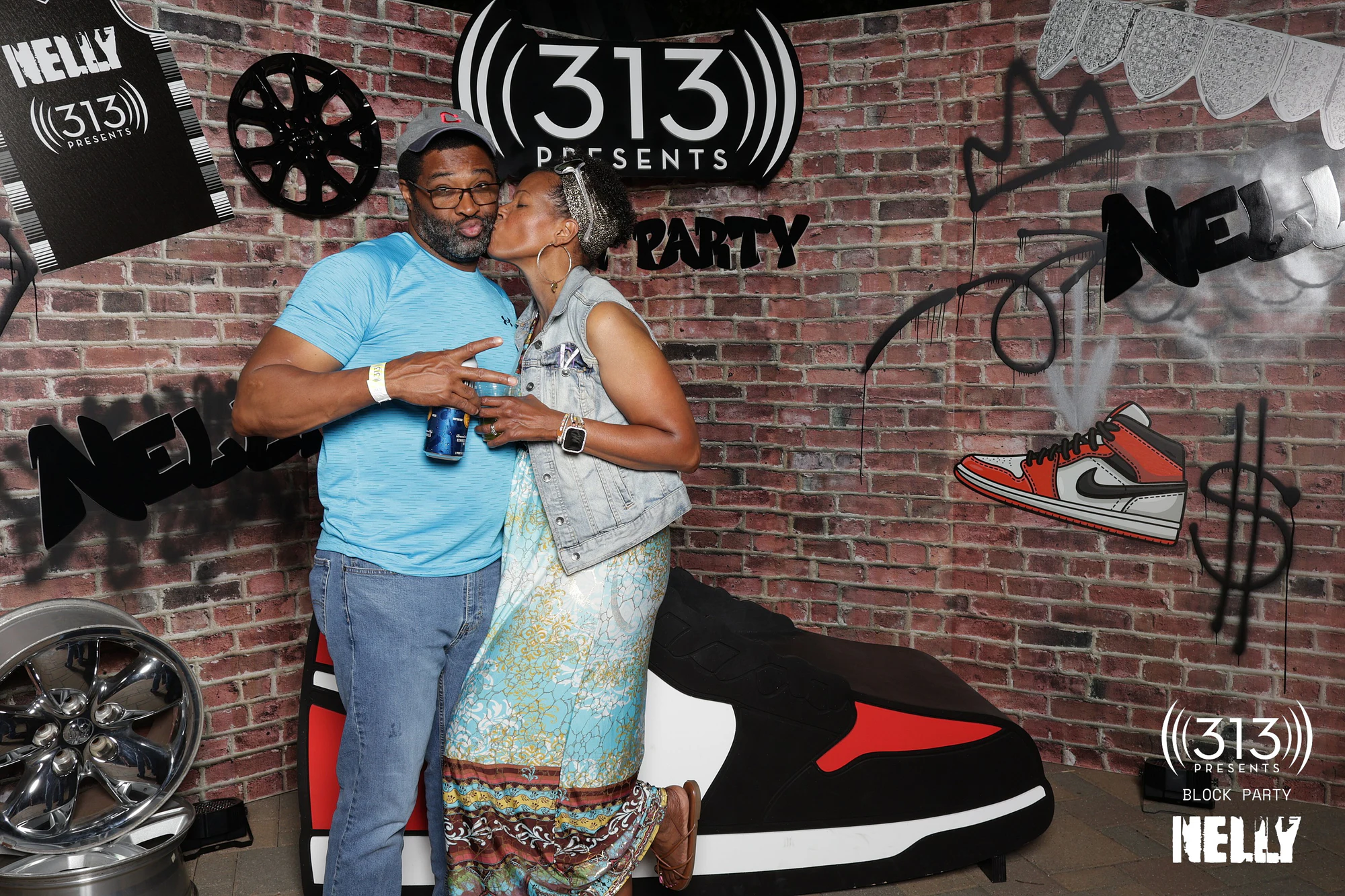 A guest kissing a friend on the cheek beside the giant sneaker at Nelly Block Party with 313 Presents