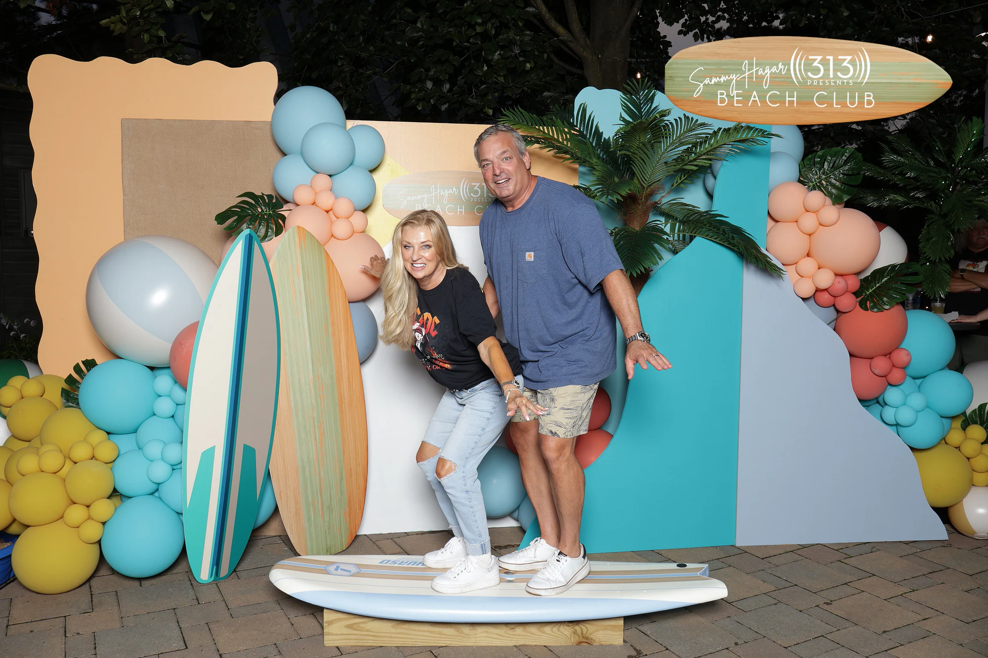 Two guests on the surfboard with their arms out, mid-laugh at Sammy Hagar at Pine Knob with 313 Presents