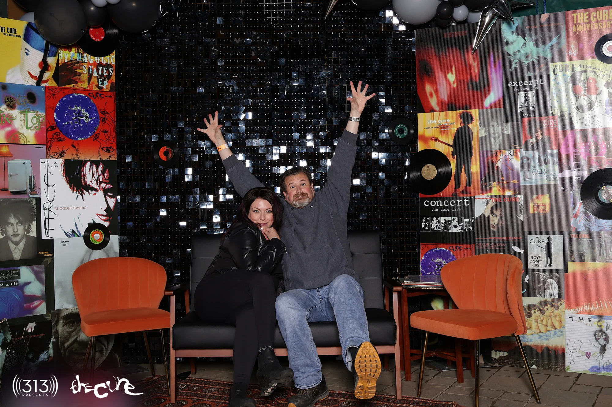 A couple on the couch with both arms up at The Cure VIP Party with 313 Presents