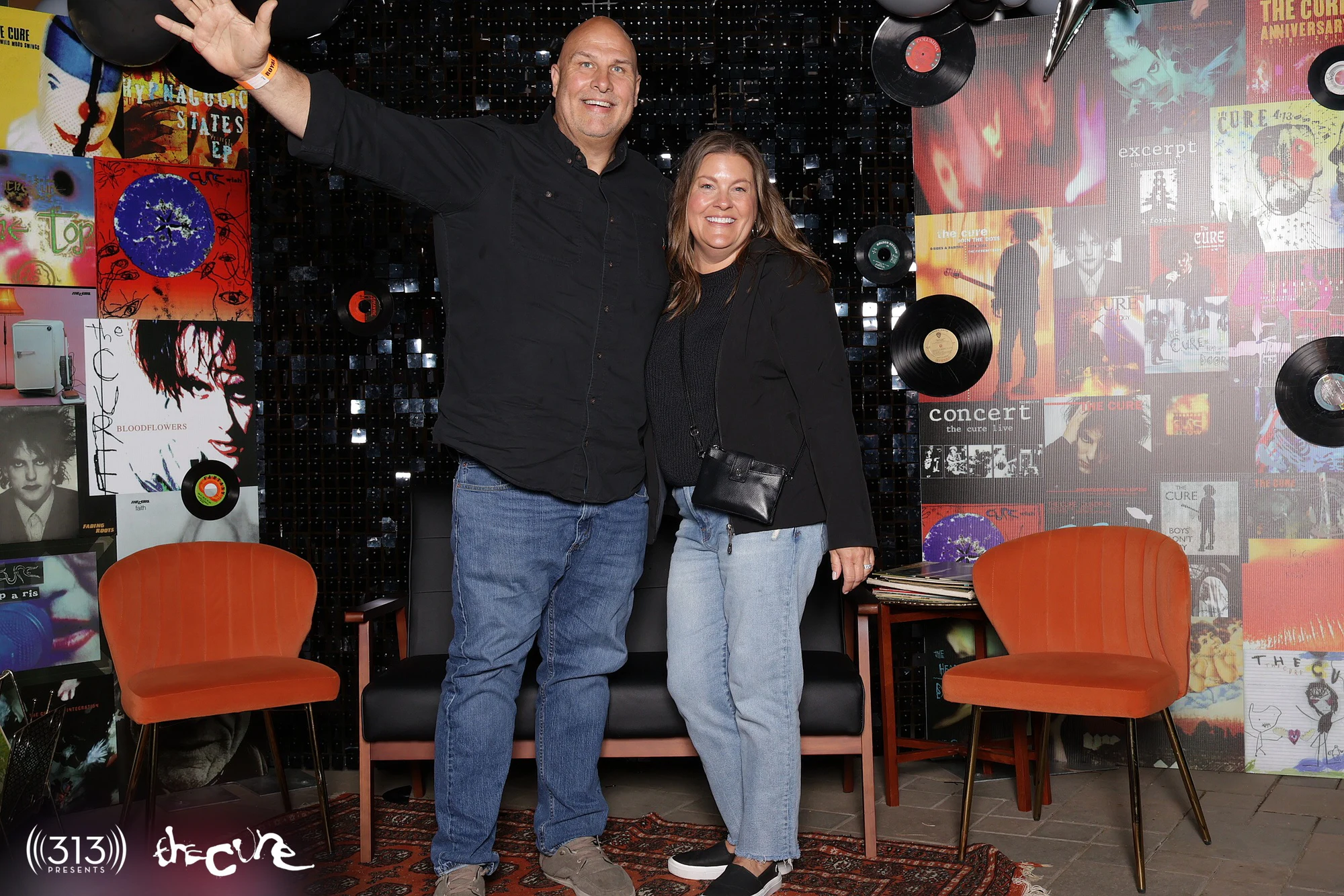 A man with his arm thrown up next to a friend at the record wall at The Cure VIP Party with 313 Presents