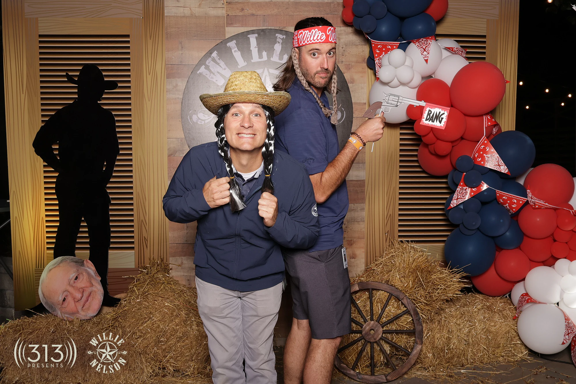Two guests, one in a straw hat and braids prop, the other pointing a flag gun at Willie Nelson VIP Party with 313 Presents