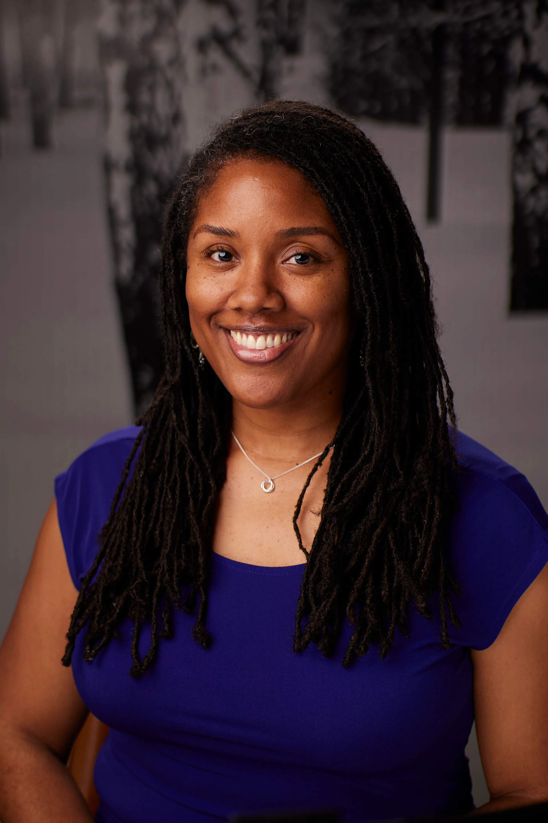 A headshot of a guest with long locs in a blue top at the AMITY Coworking grand reopening