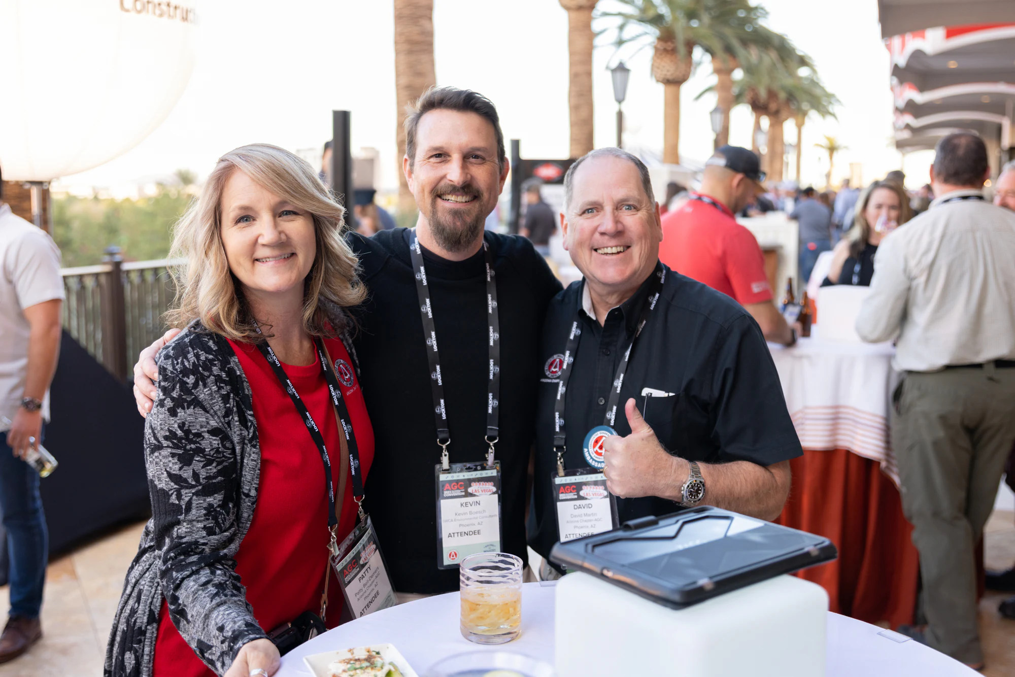 Three guests posed at a cocktail table, drinks in hand at Autodesk at the AGC Annual Convention 2023