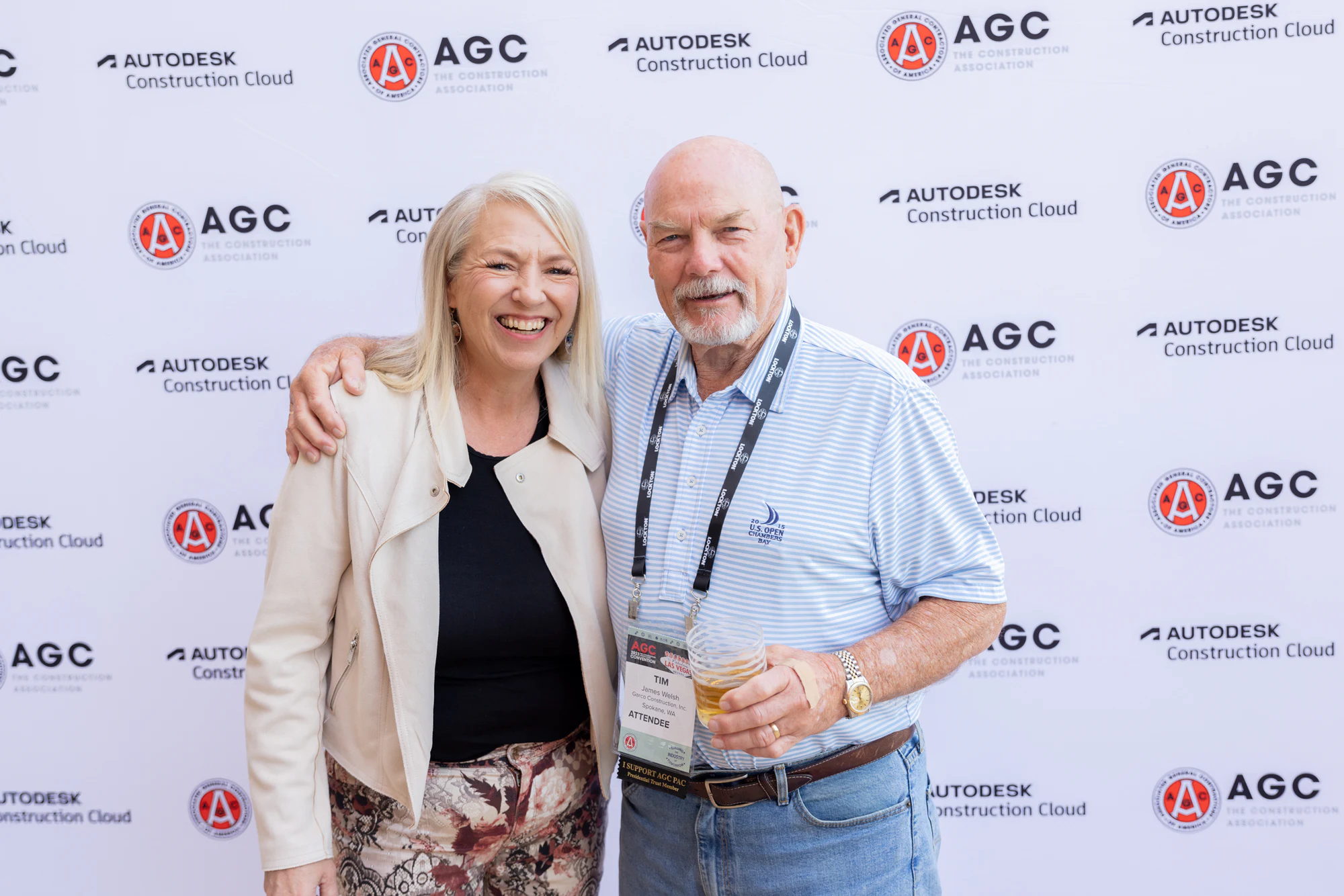 A couple smiling in front of the AGC step-and-repeat at Autodesk at the AGC Annual Convention 2023