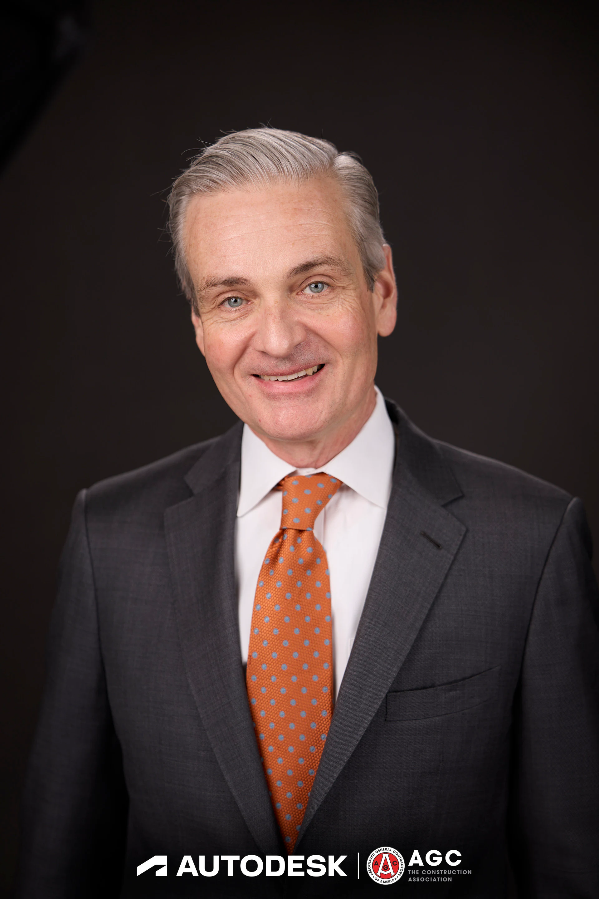 A headshot of a guest in a grey suit and an orange tie at Autodesk at the AGC Annual Convention 2025