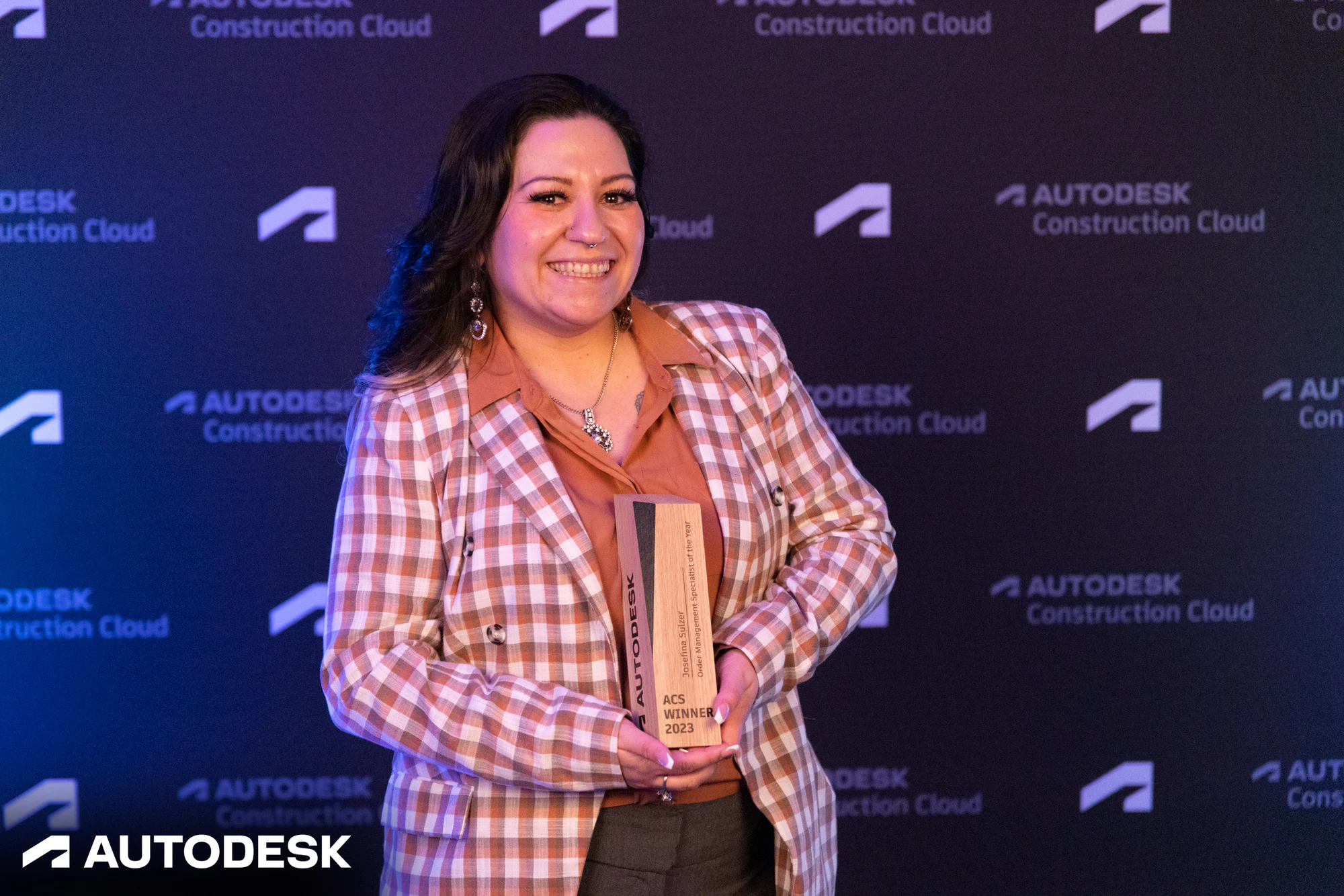 The winner smiling with her trophy at the Autodesk OTC Awards 2023