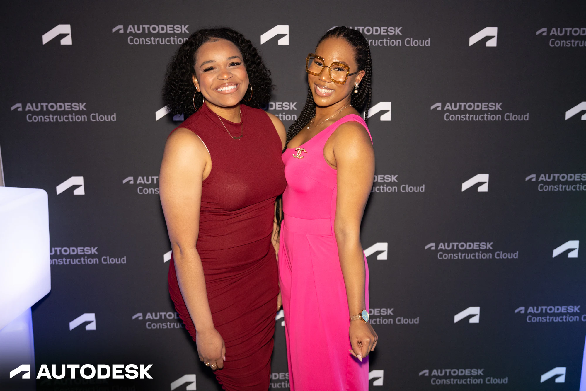Two guests in red and pink at the step and repeat at Autodesk Awards Atlanta 2023