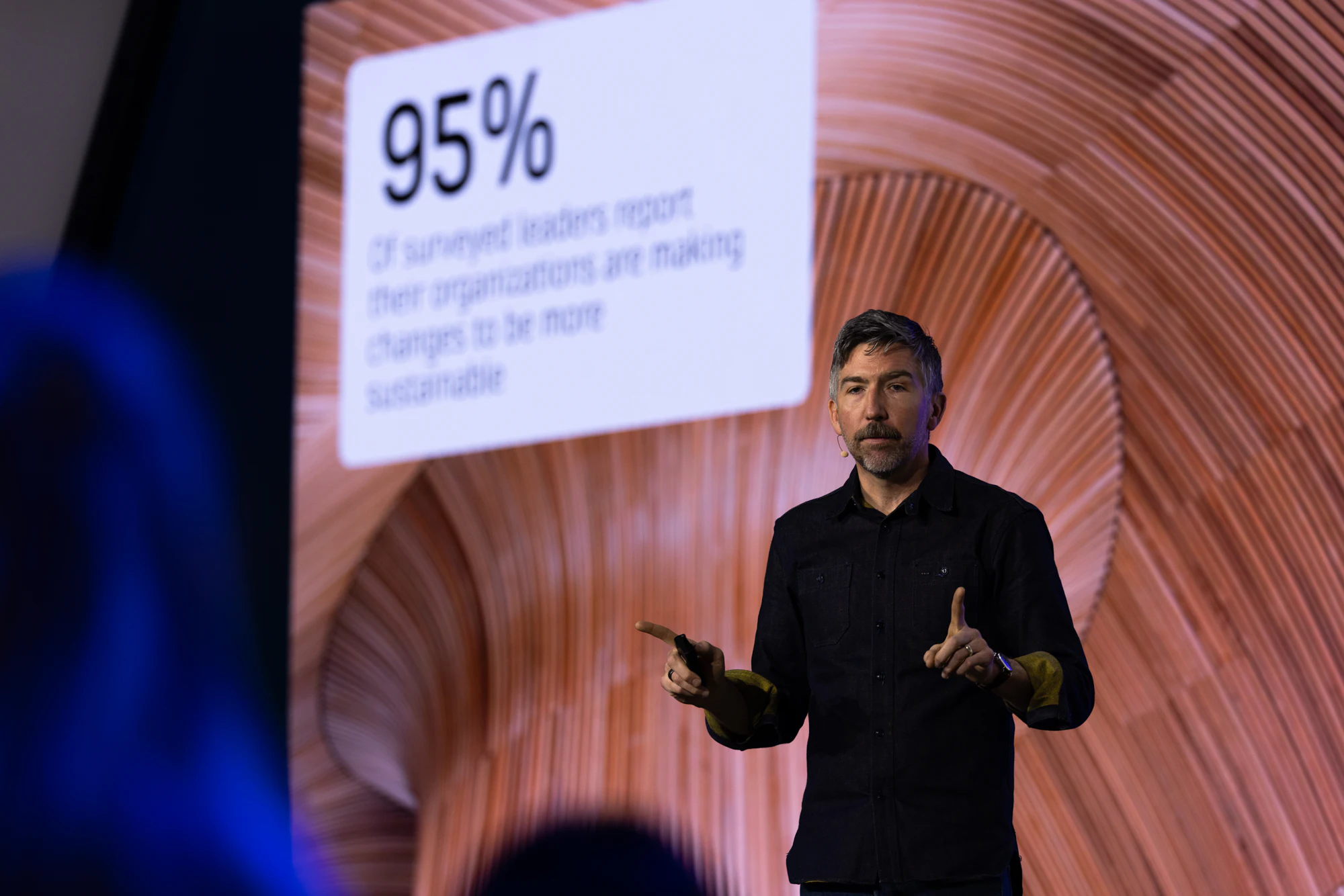 The keynote: a speaker in a dark shirt in front of a slide that begins “95%” at Autodesk at CONEXPO-CON/AGG 2026