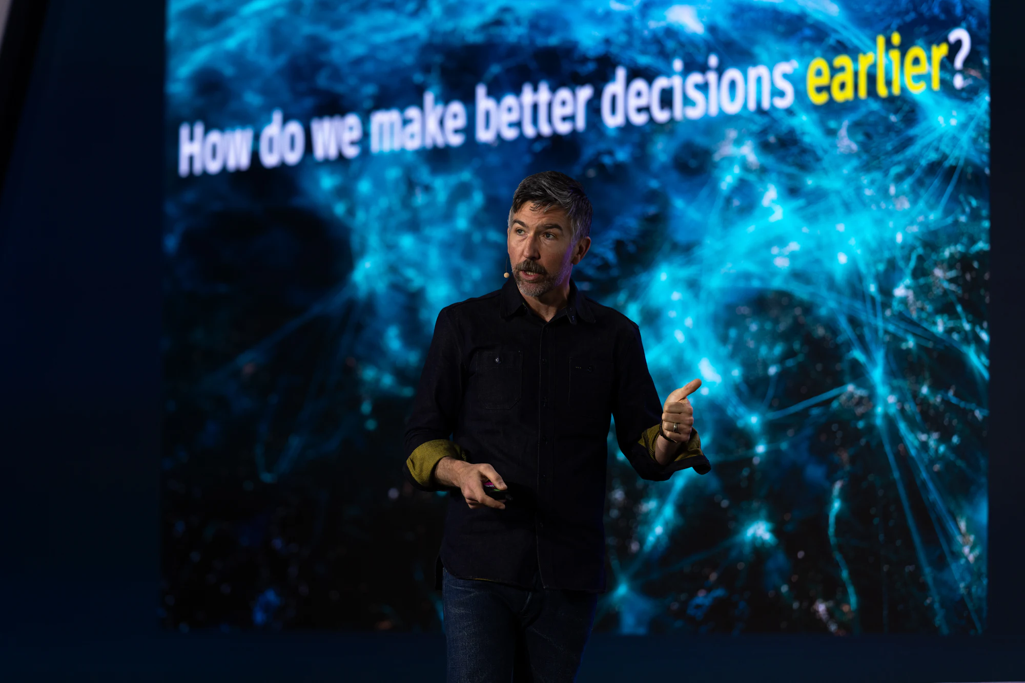 The keynote: the same speaker under the slide “How do we make better decisions earlier?” at Autodesk at CONEXPO-CON/AGG 2026