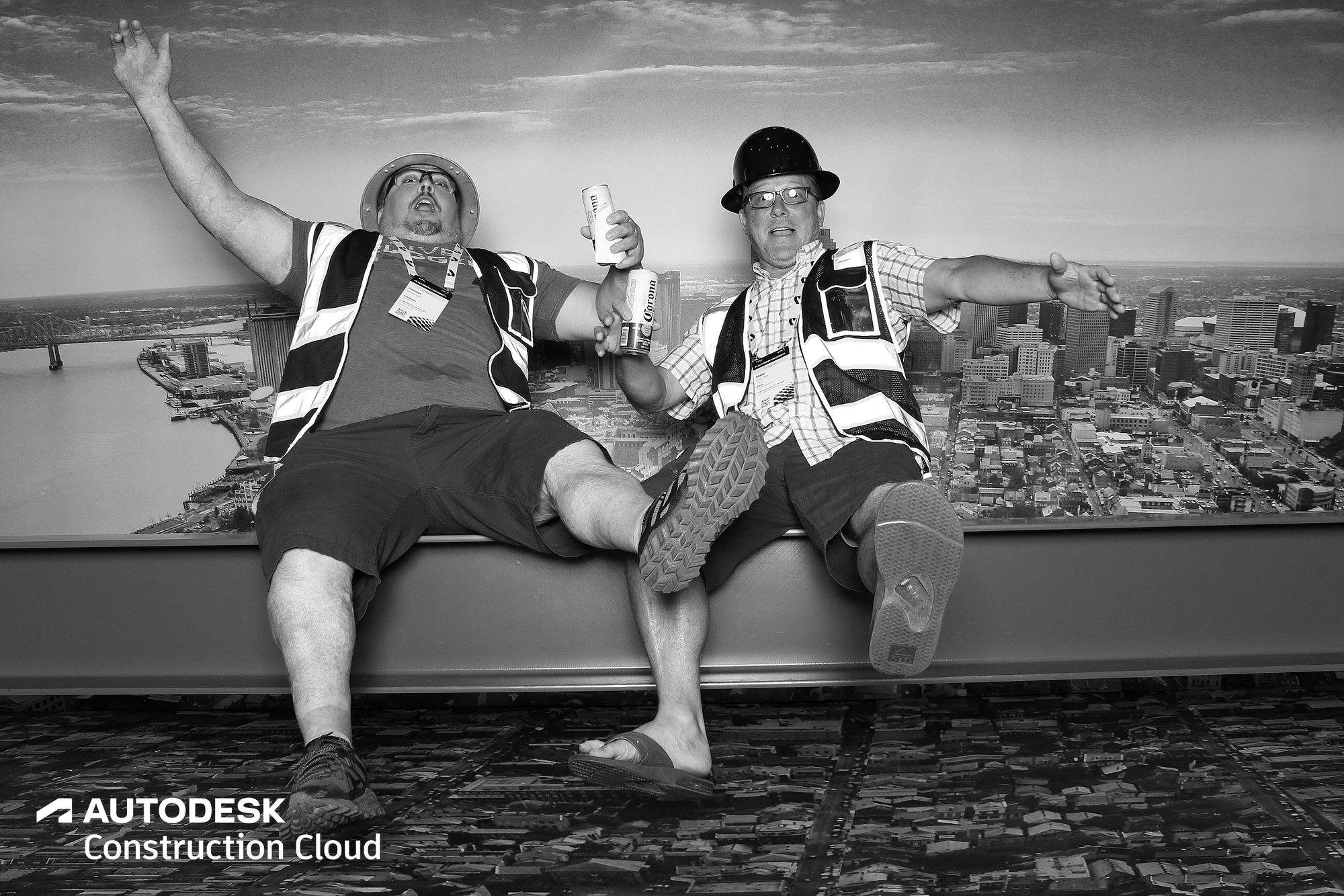 Two guys throwing their arms up, one in shorts and a hard hat at Autodesk University 2022