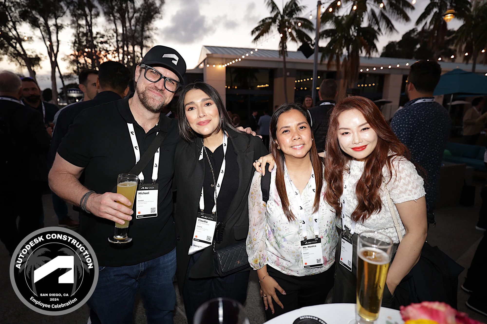 Five with drinks under the string lights, laughing at Autodesk University 2024