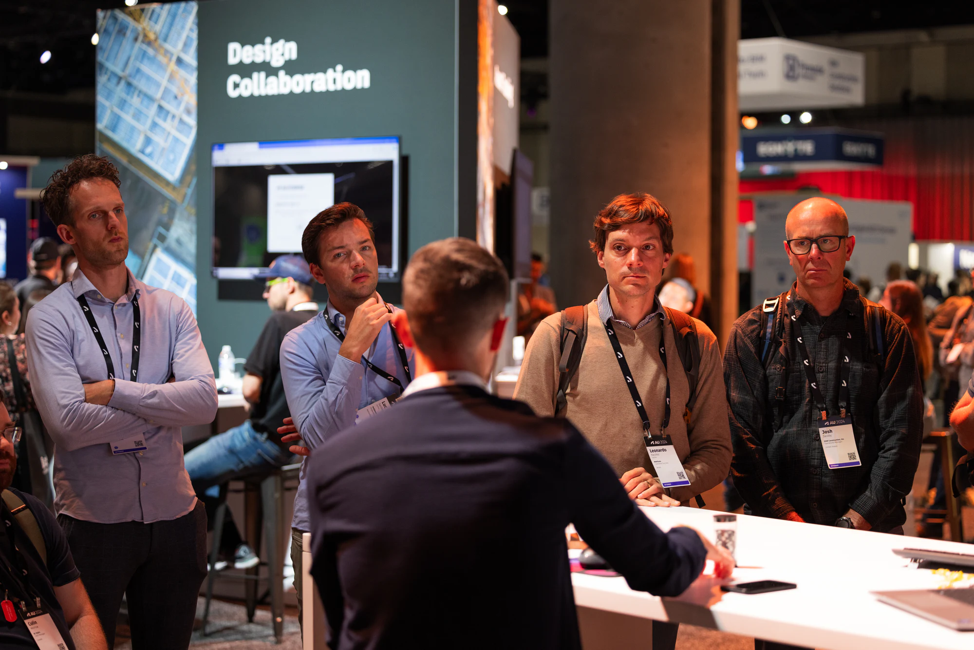 Attendees in lanyards watching a demo at the Design Collaboration station at Autodesk University 2024