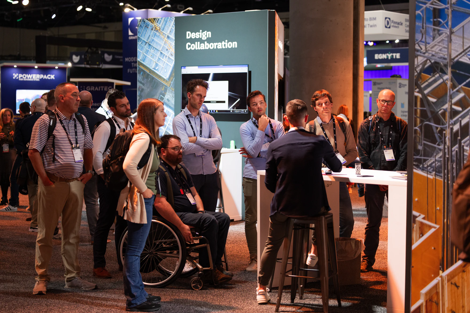 A wider look at the crowd standing around the Design Collaboration demo table at Autodesk University 2024