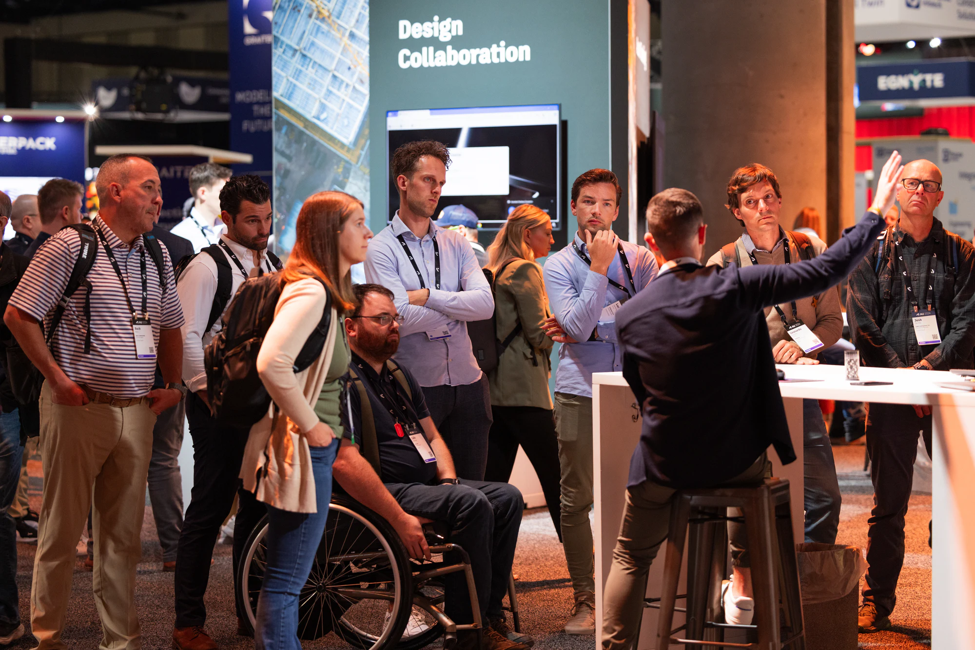 The presenter pointing to the screen while the crowd watches at the Design Collaboration station at Autodesk University 2024