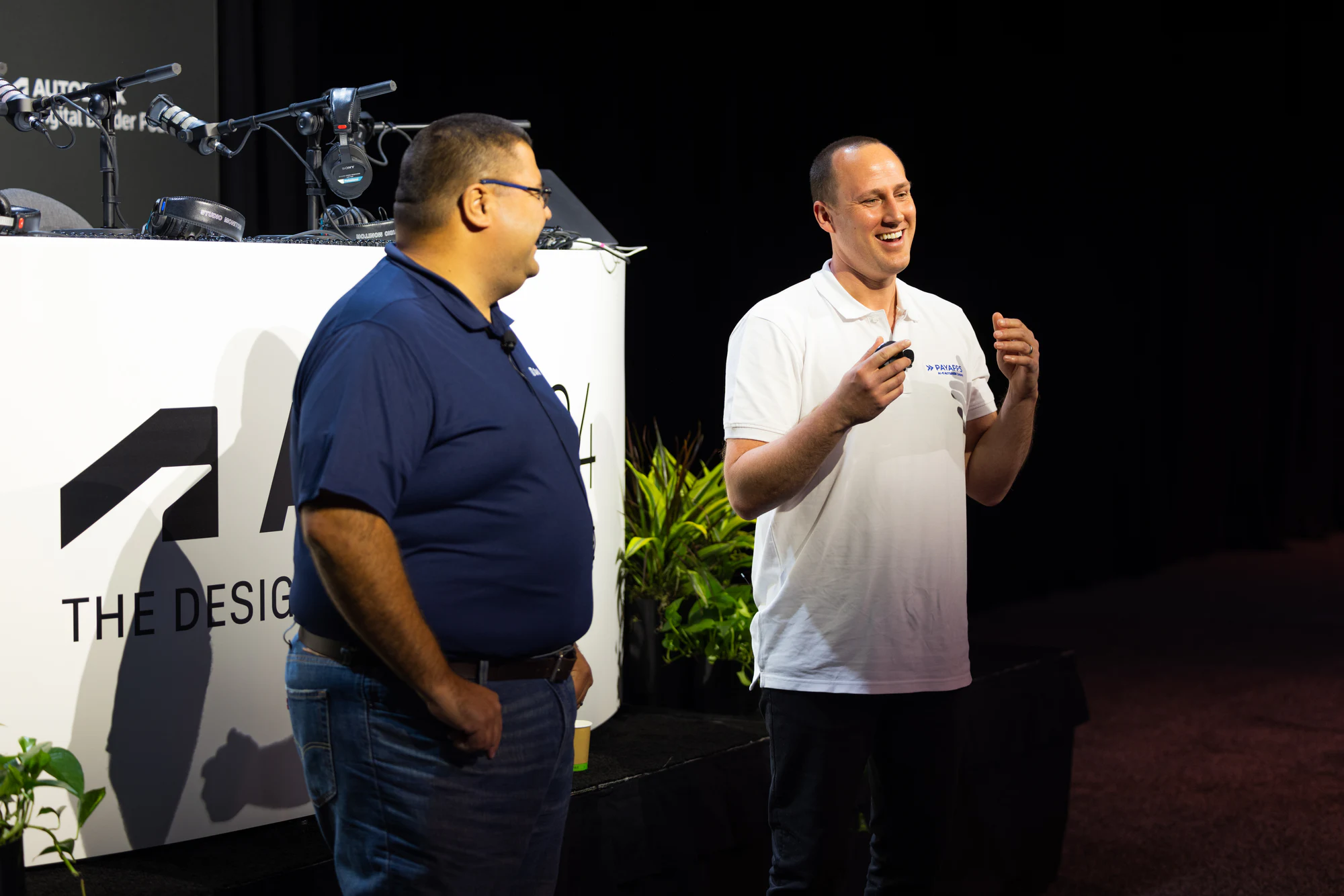 The presenter in the white polo talking with his hands, his co-presenter beside him at Autodesk University 2024