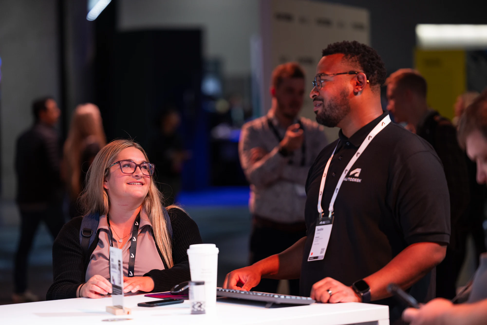 An attendee smiling at a demo station as an Autodesk staffer walks her through it at Autodesk University 2024