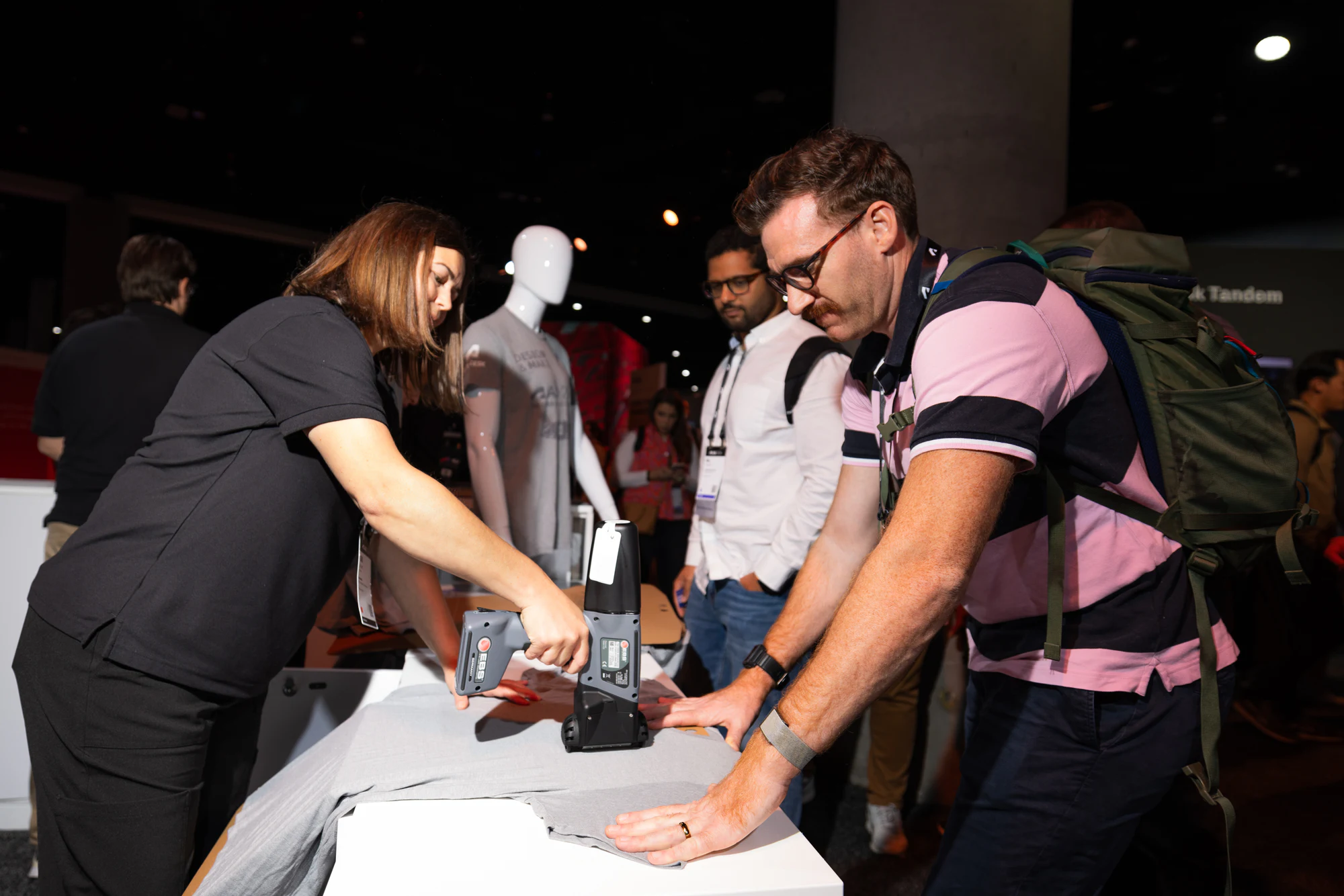 Another attendee in a striped polo lining up his T-shirt at the merch station at Autodesk University 2024