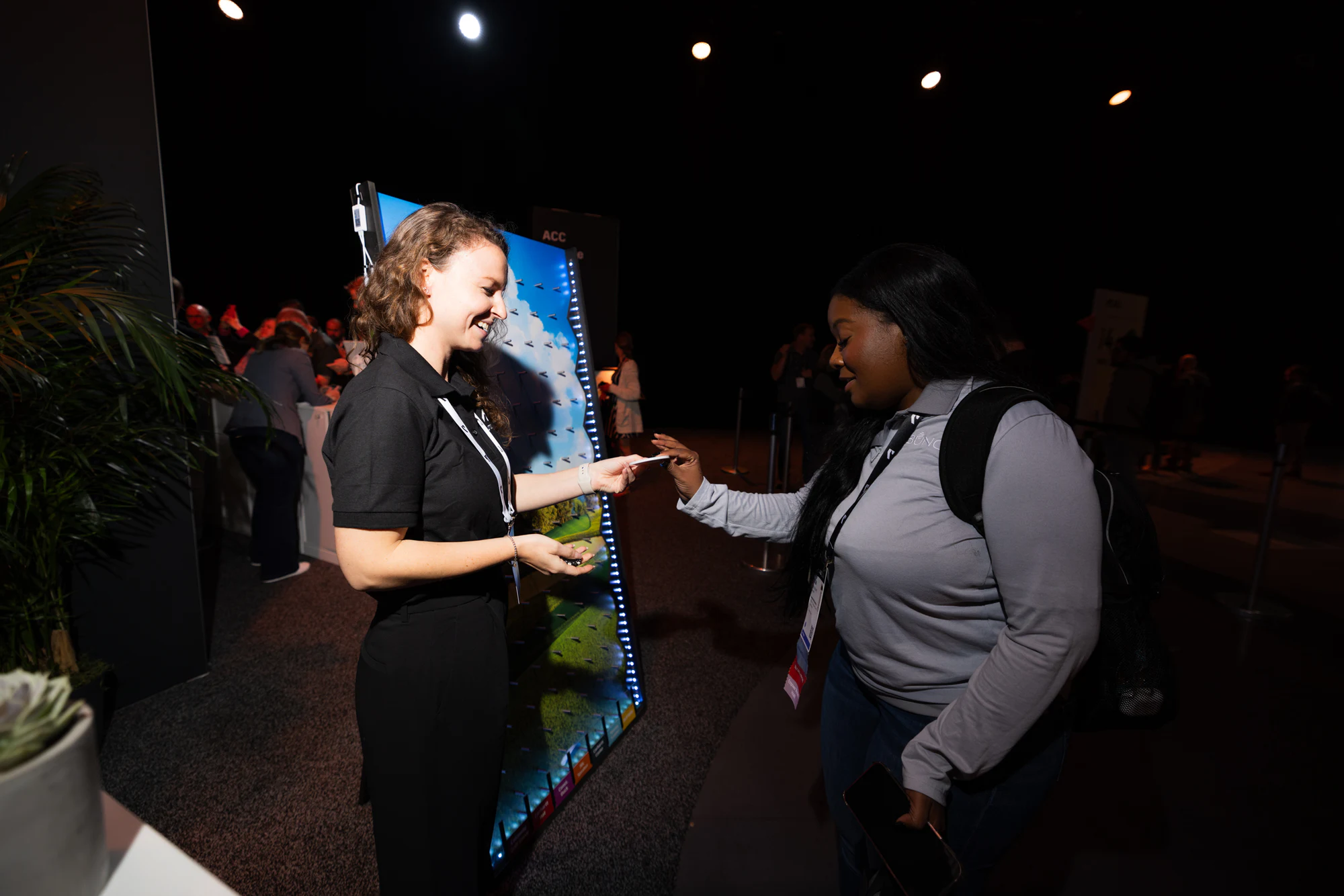 A staffer showing an attendee the lit pin wall at a booth on the show floor at Autodesk University 2024