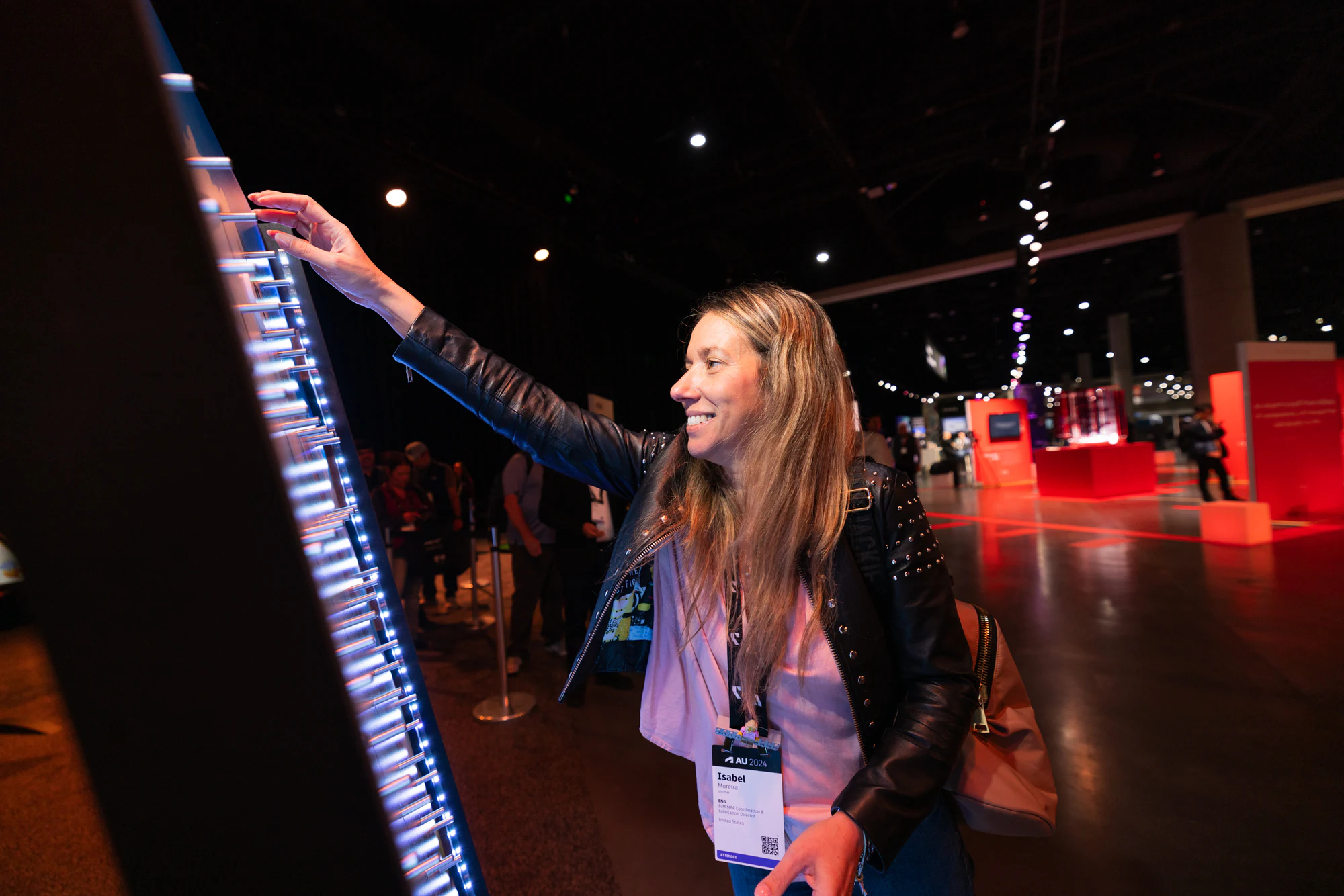 The same attendee pressing pins lower down on the lit wall at Autodesk University 2024