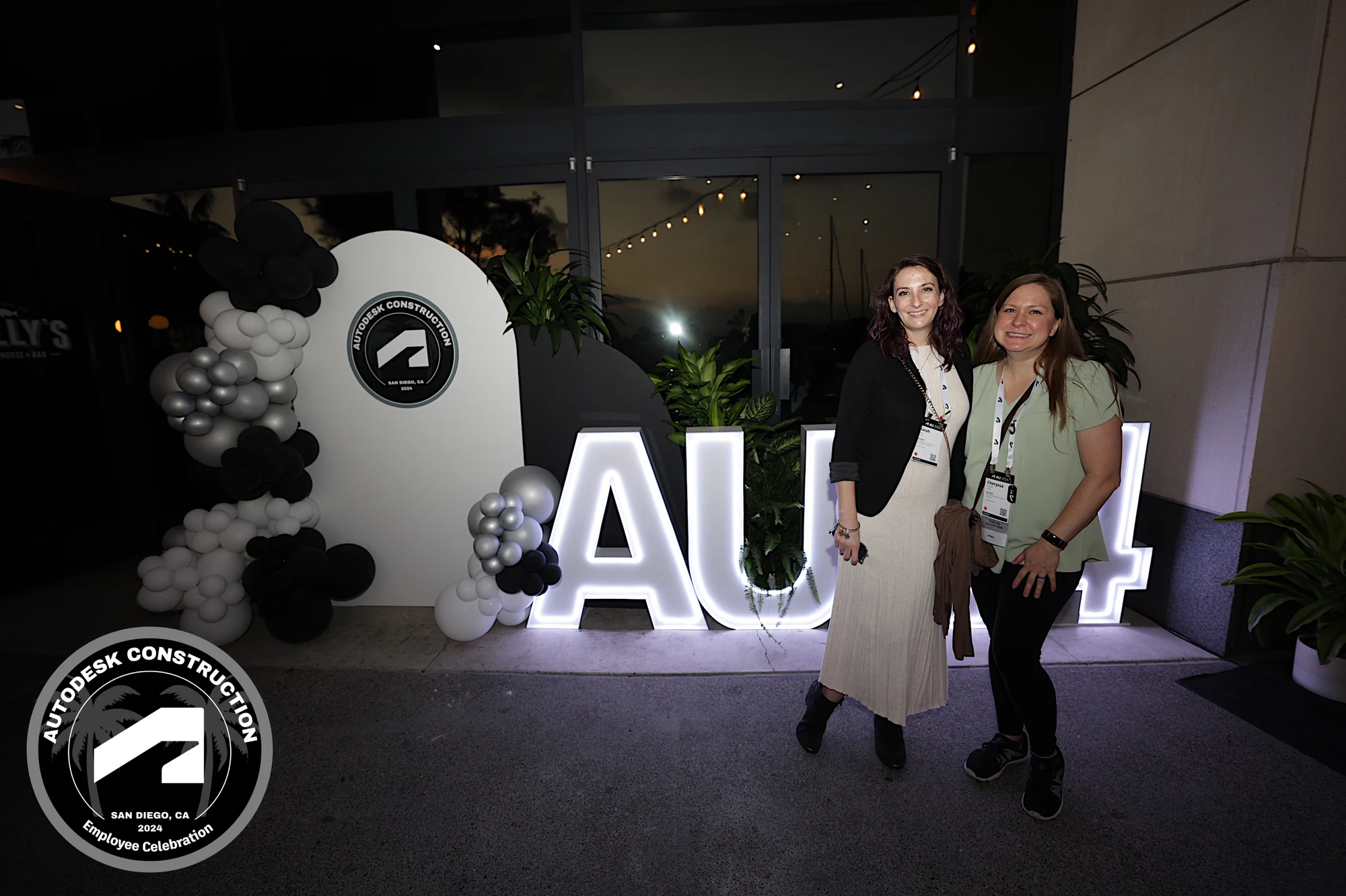Two coworkers standing together at the lit AU24 letters at Autodesk University 2024