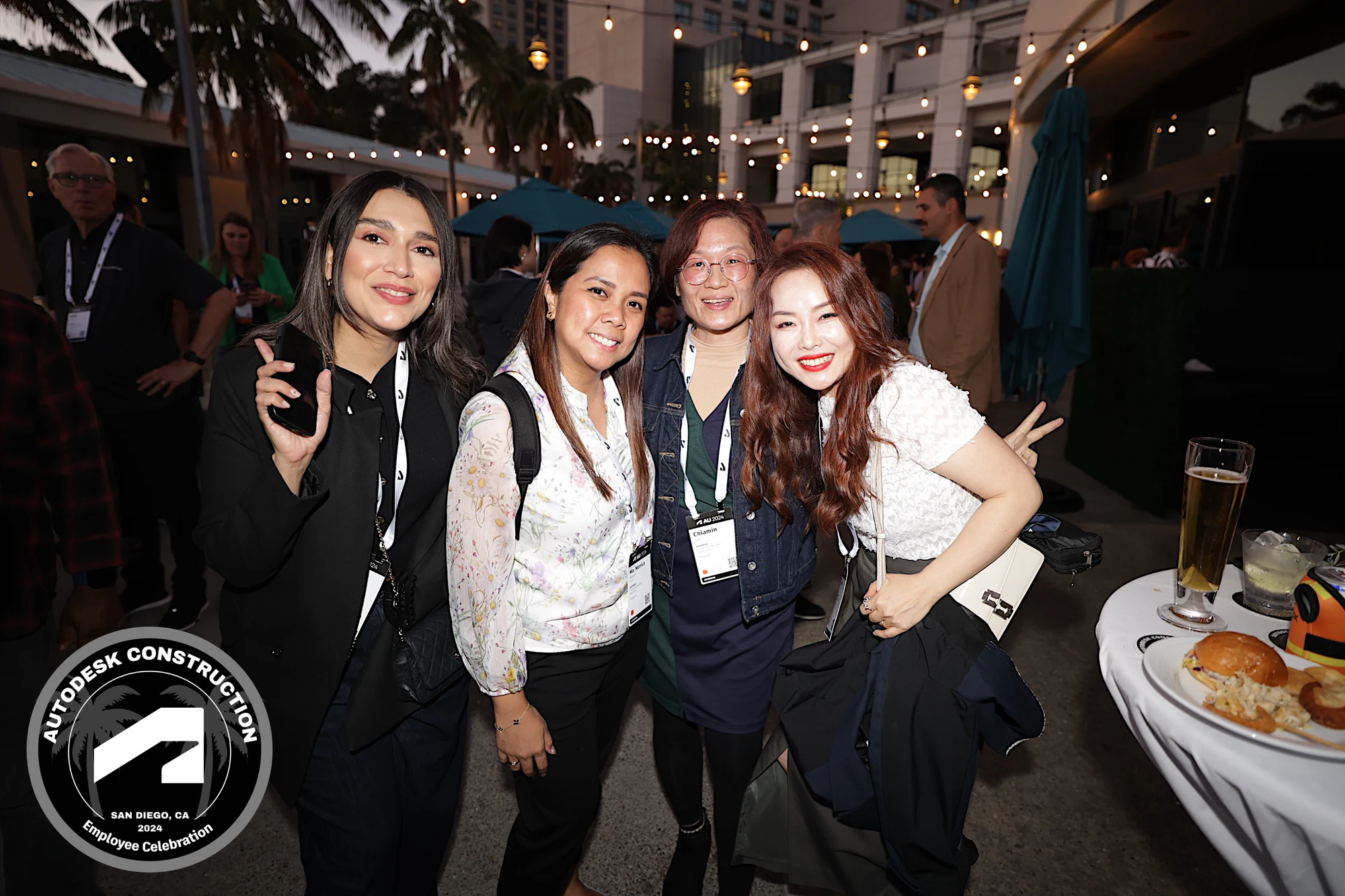 Four coworkers in lanyards on the terrace, one throwing a peace sign at Autodesk University 2024