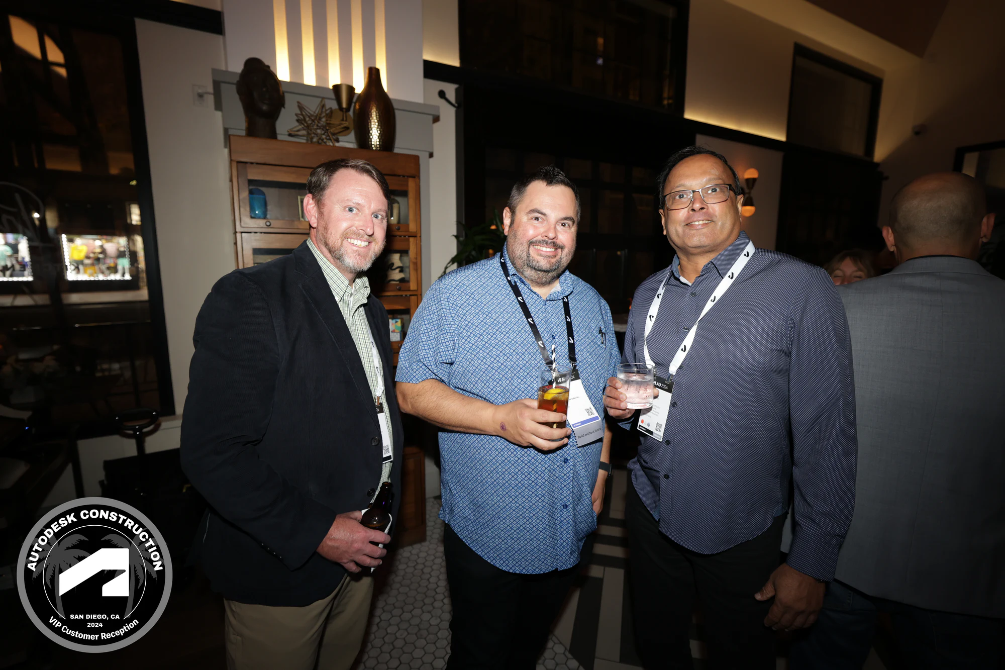 VIP reception: three guests in lanyards with drinks at Autodesk University 2024
