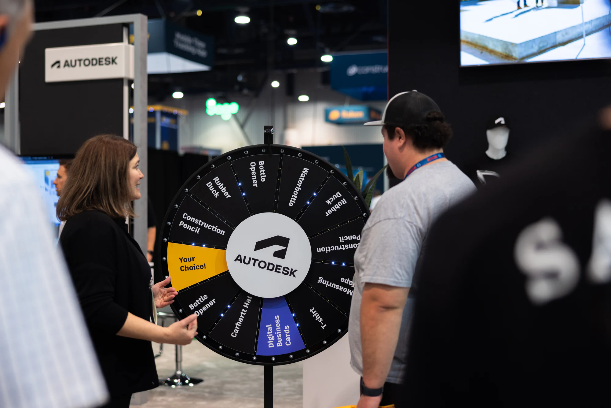 She talks a visitor through the prize wheel at Autodesk at World of Concrete 2024