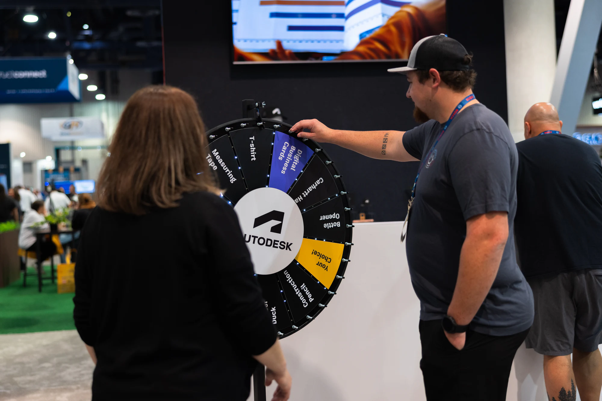 The visitor spins the prize wheel while she watches at Autodesk at World of Concrete 2024