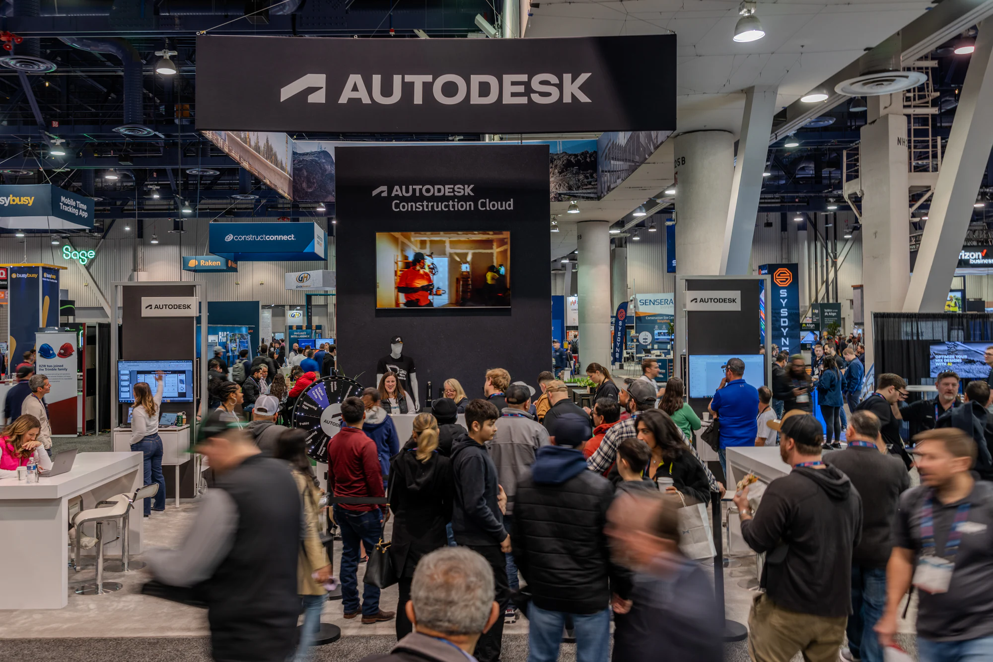 The booth busy with visitors around the demo screens at Autodesk at World of Concrete 2024