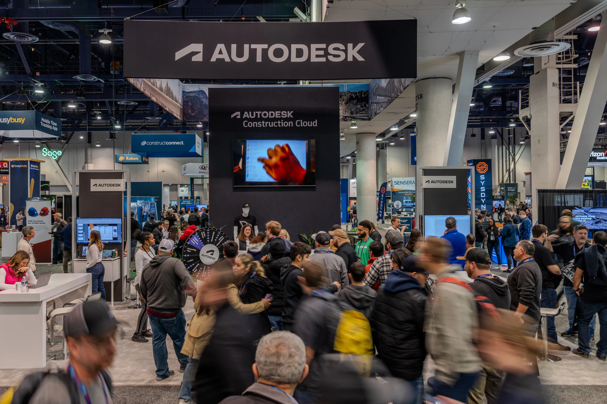 A crowd moving through the booth in front of the video wall at Autodesk at World of Concrete 2024