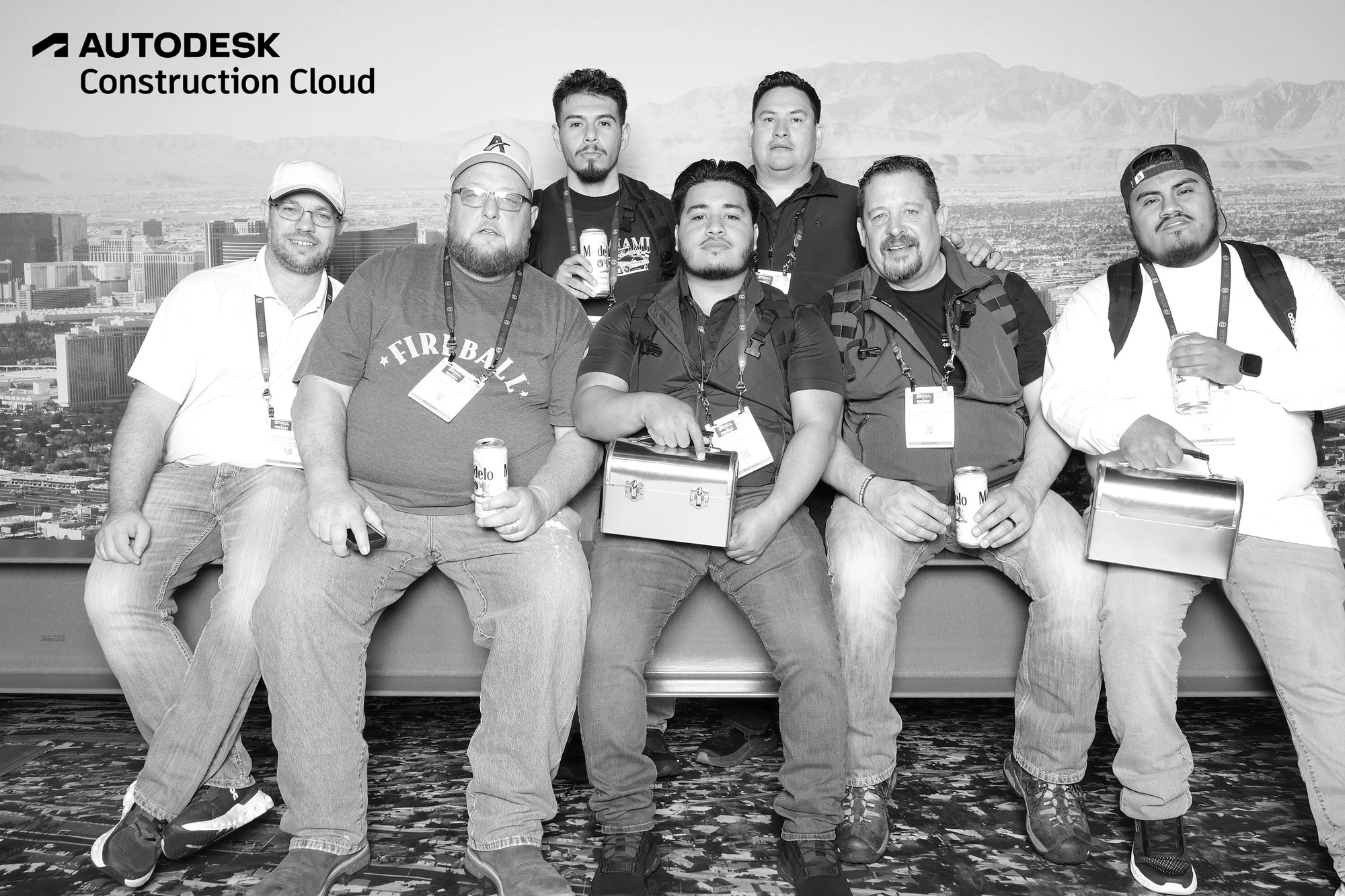 Seven guests on the steel beam with lunchboxes over the Las Vegas skyline, in black and white at Autodesk at World of Concrete 2025