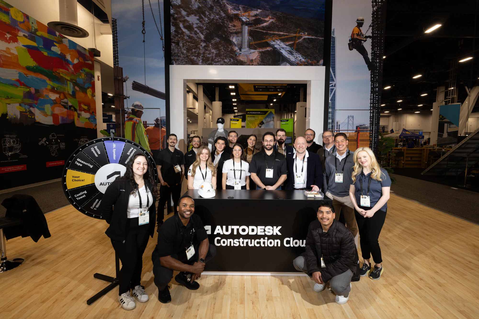 The Autodesk Construction Cloud booth team posed around the front desk and prize wheel at Autodesk at World of Concrete 2025