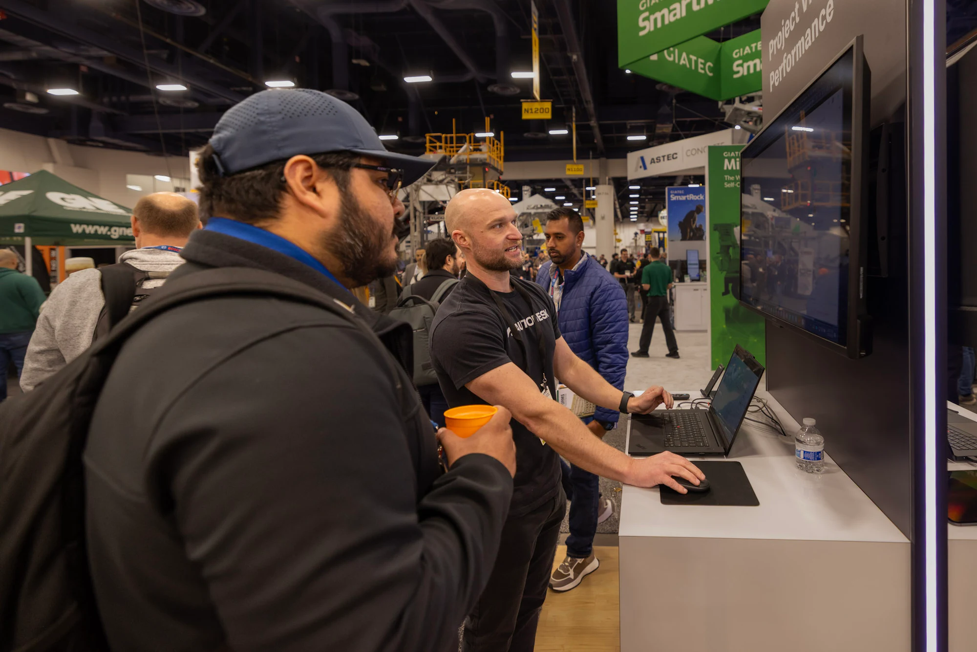 An Autodesk team member walking a visitor through a demo on the laptop at Autodesk at World of Concrete 2026