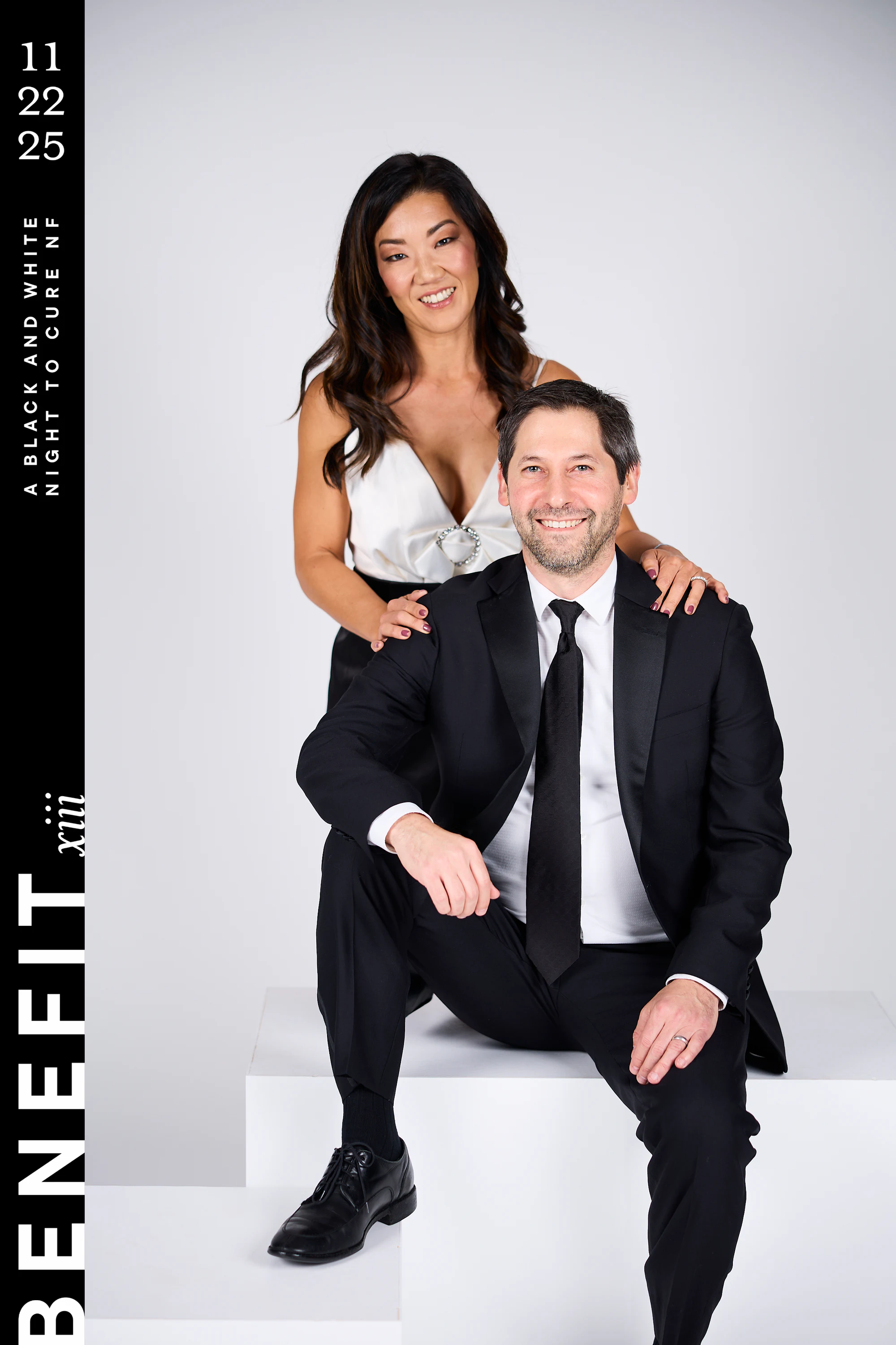 The same couple closer in, him seated with a hand on his knee at beNeFit XIII