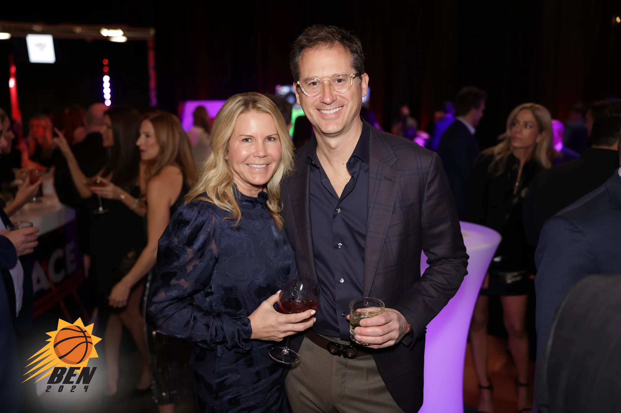 A couple with drinks beside a glowing cocktail table at Ben’s Bar Mitzvah