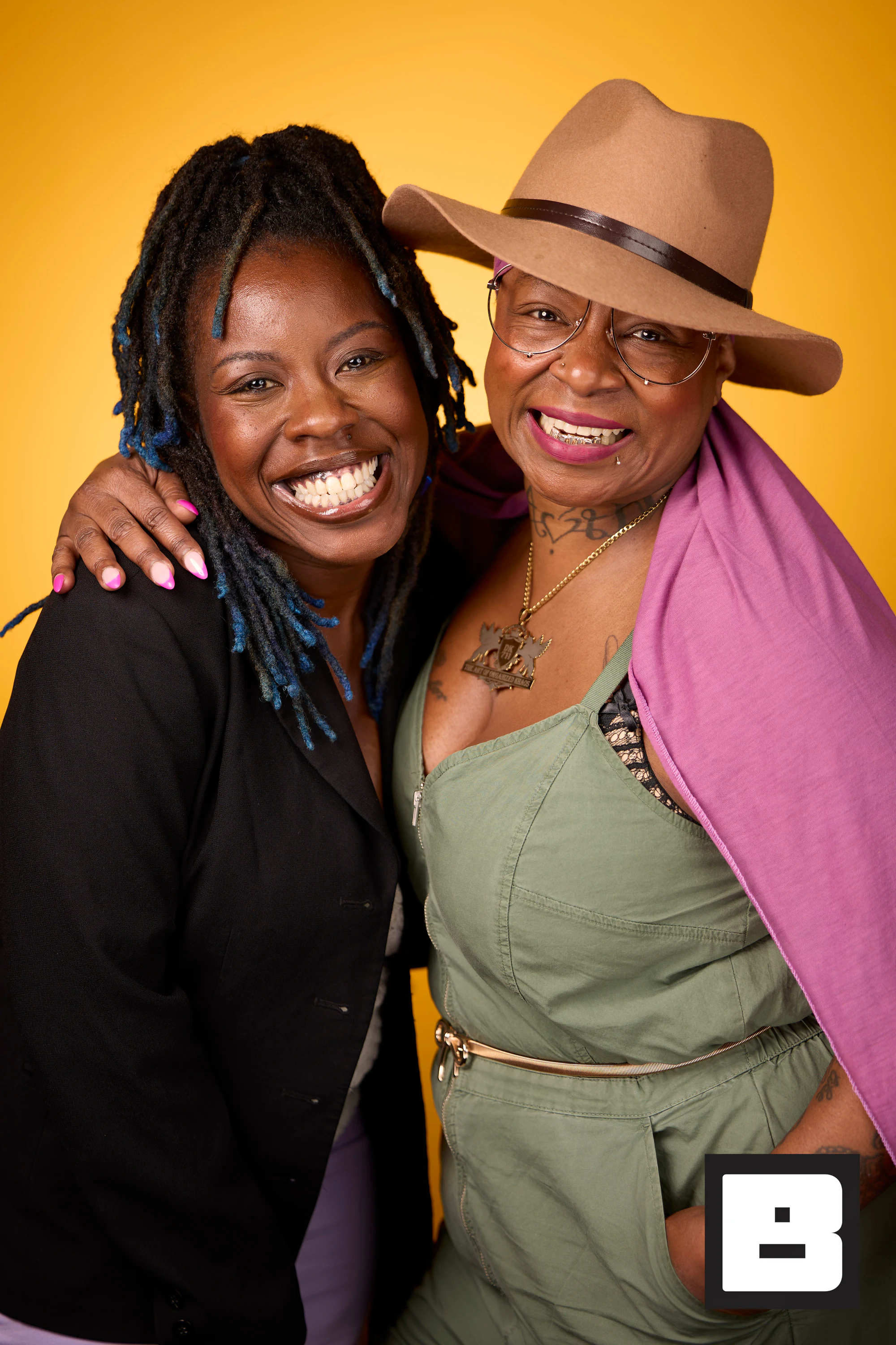 Two guests hugging for a portrait, one in a tan fedora and a pink shawl at Black Tech Week 2025