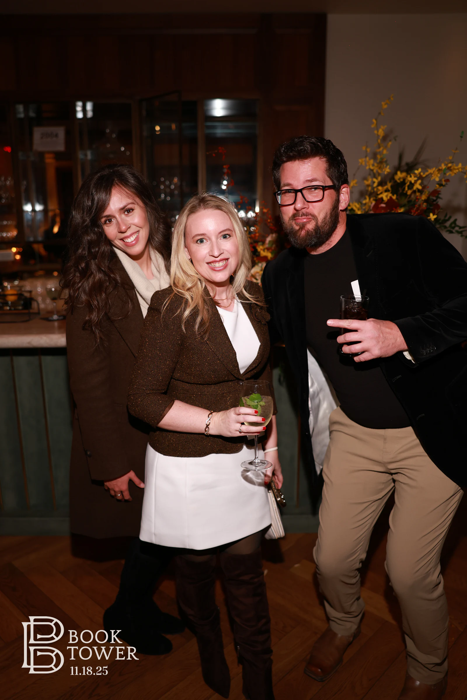 Three guests with drinks in front of the bar at the Book Tower vendor event