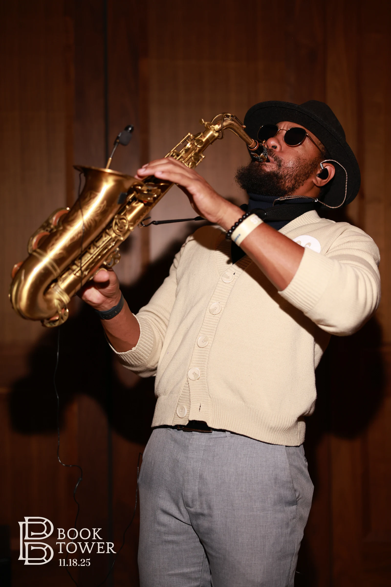 A saxophonist in a hat and cardigan mid-song at the Book Tower vendor event