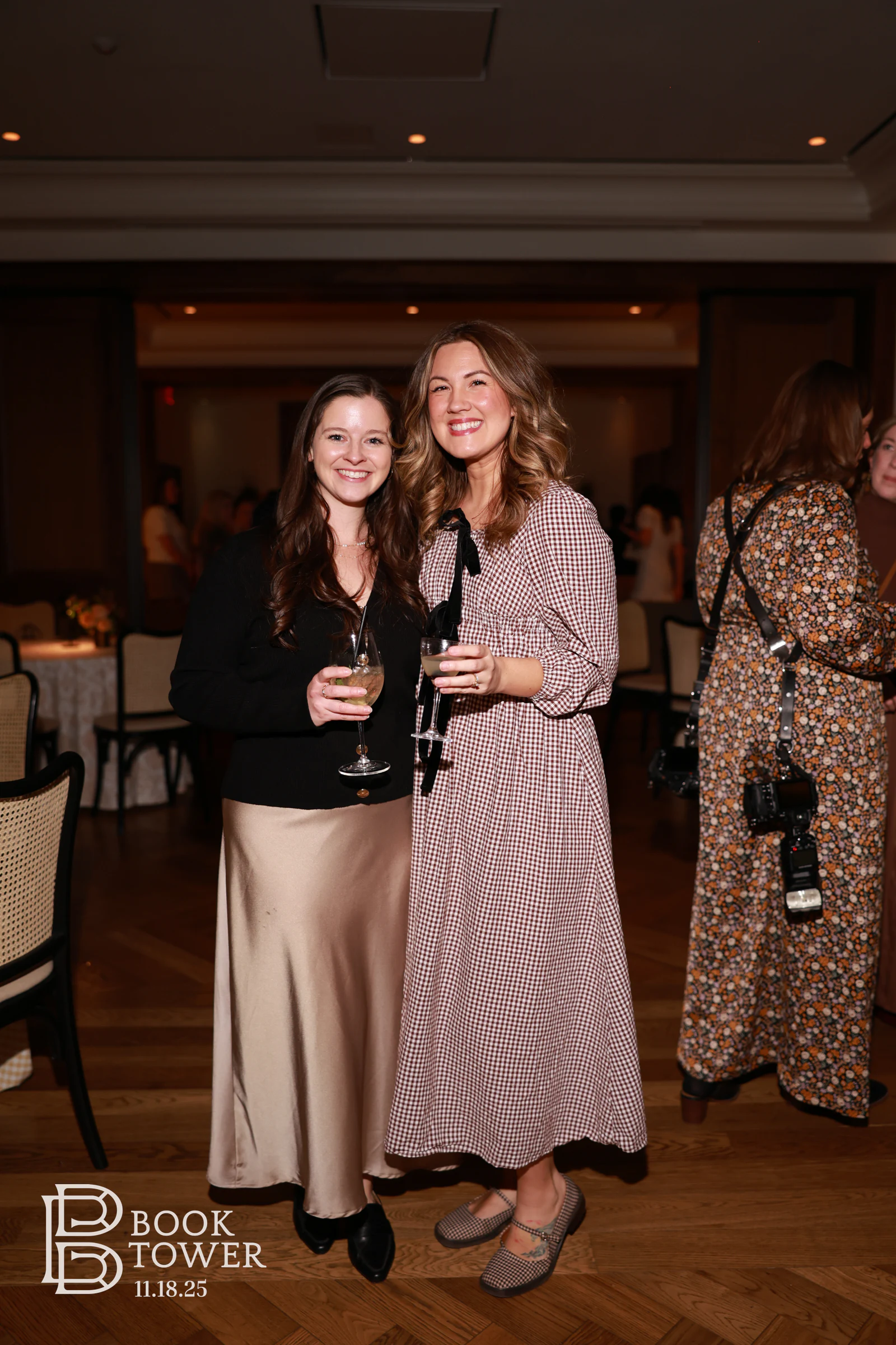 Two guests with wine glasses on the herringbone floor at the Book Tower vendor event